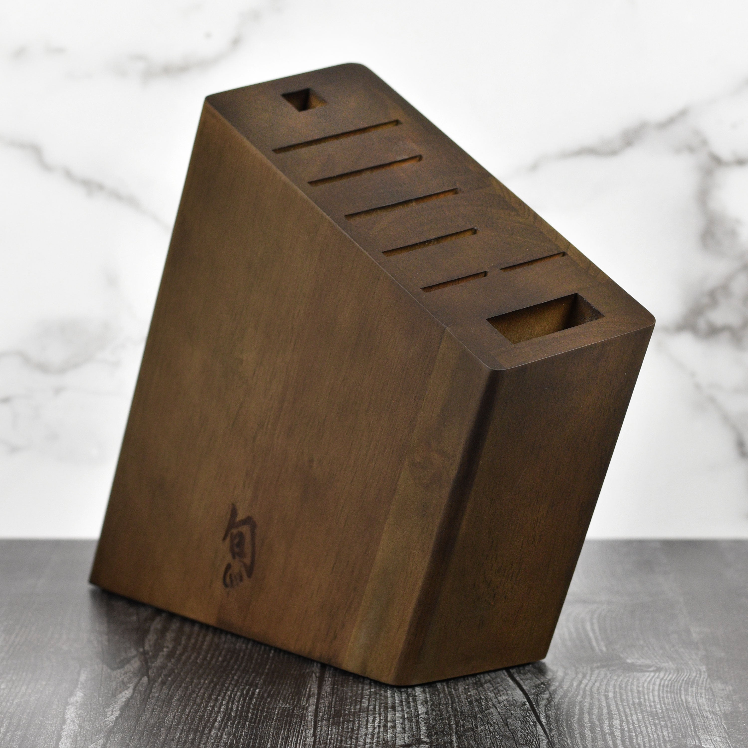 Close-up of dark wood angled knife block with multiple slots for knives and accessories