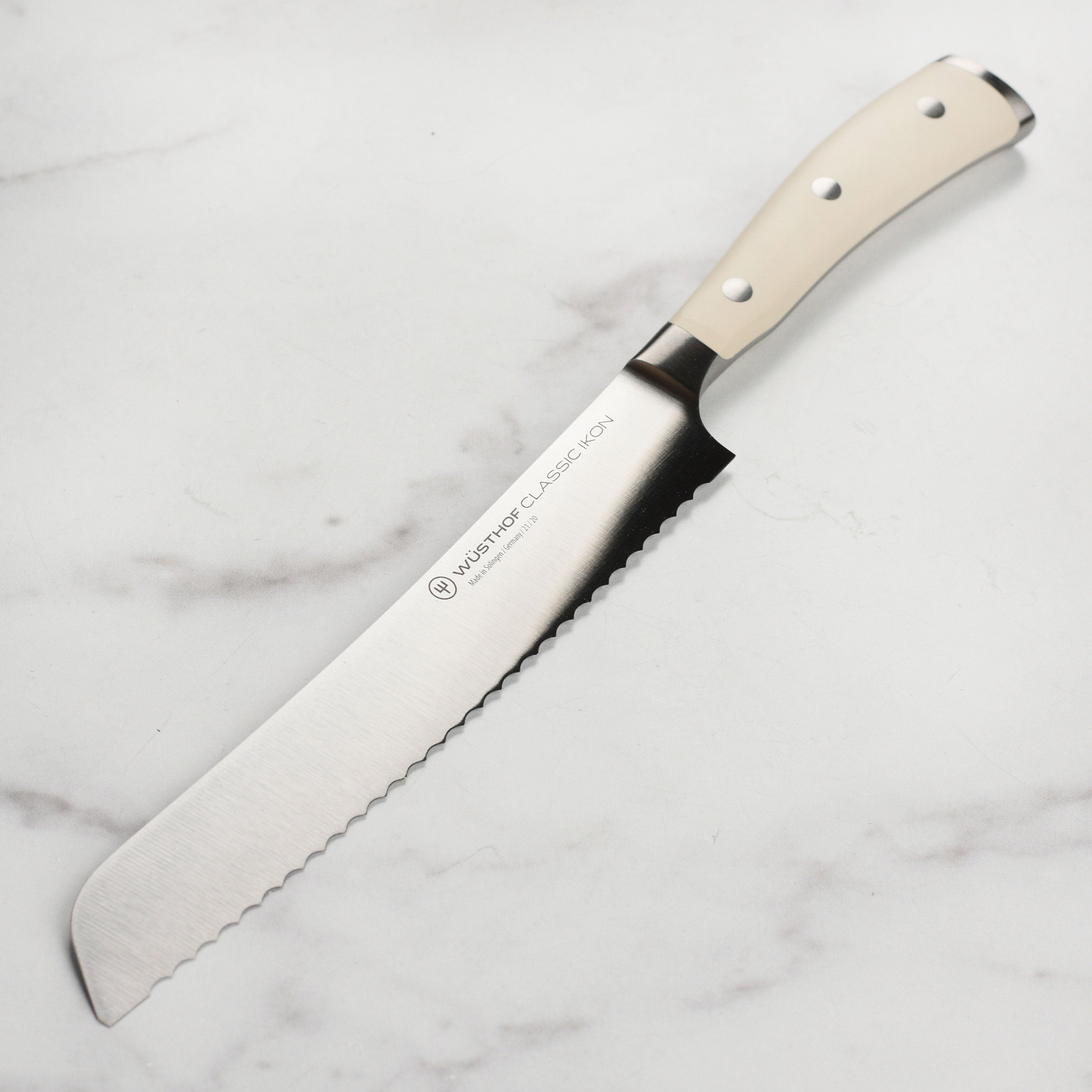 Close-up of Wusthof Classic Ikon Creme 8-inch bread knife blade slicing bread