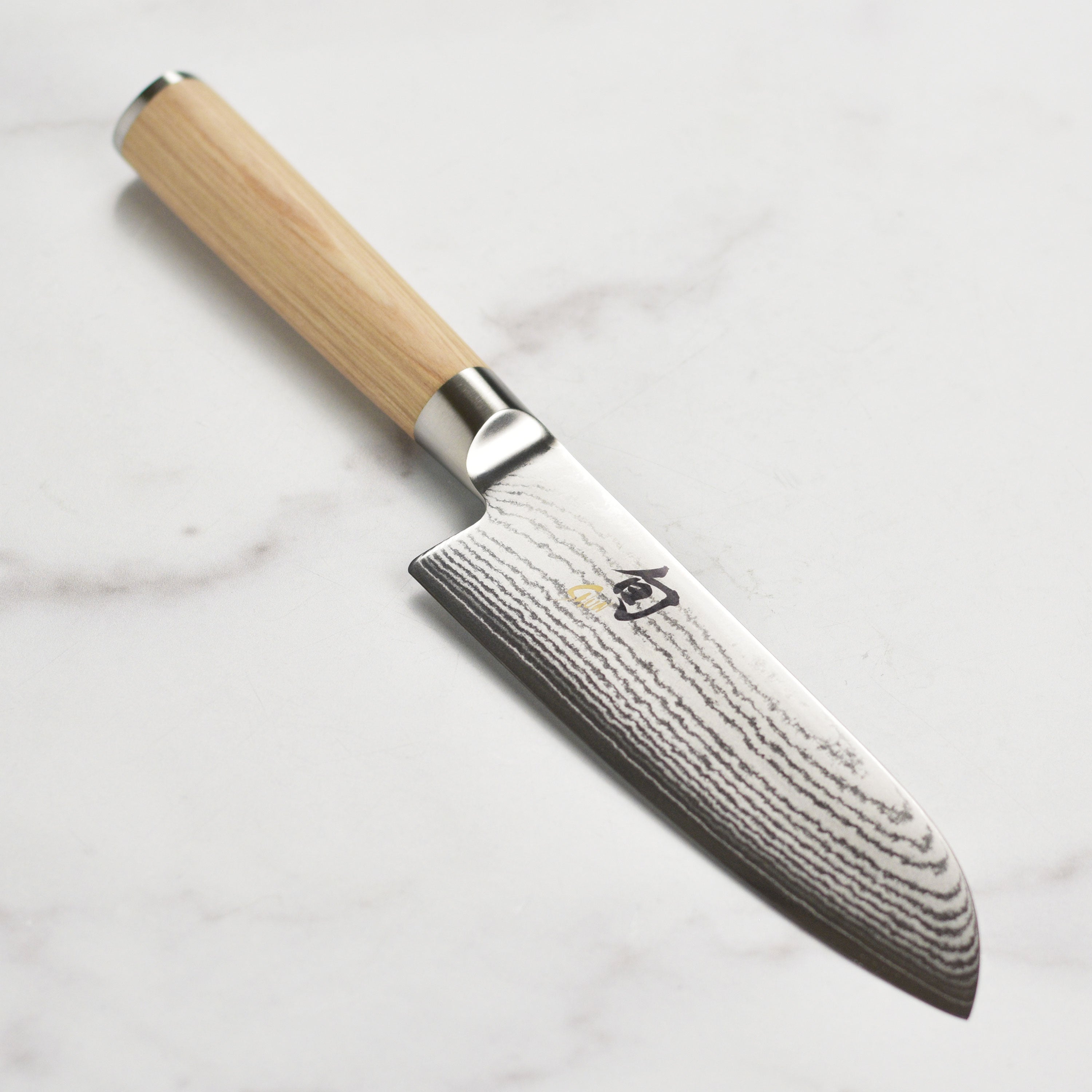 Close-up of the Shun Classic Blonde Santoku knife showcasing the Damascus blade and PakkaWood handle.