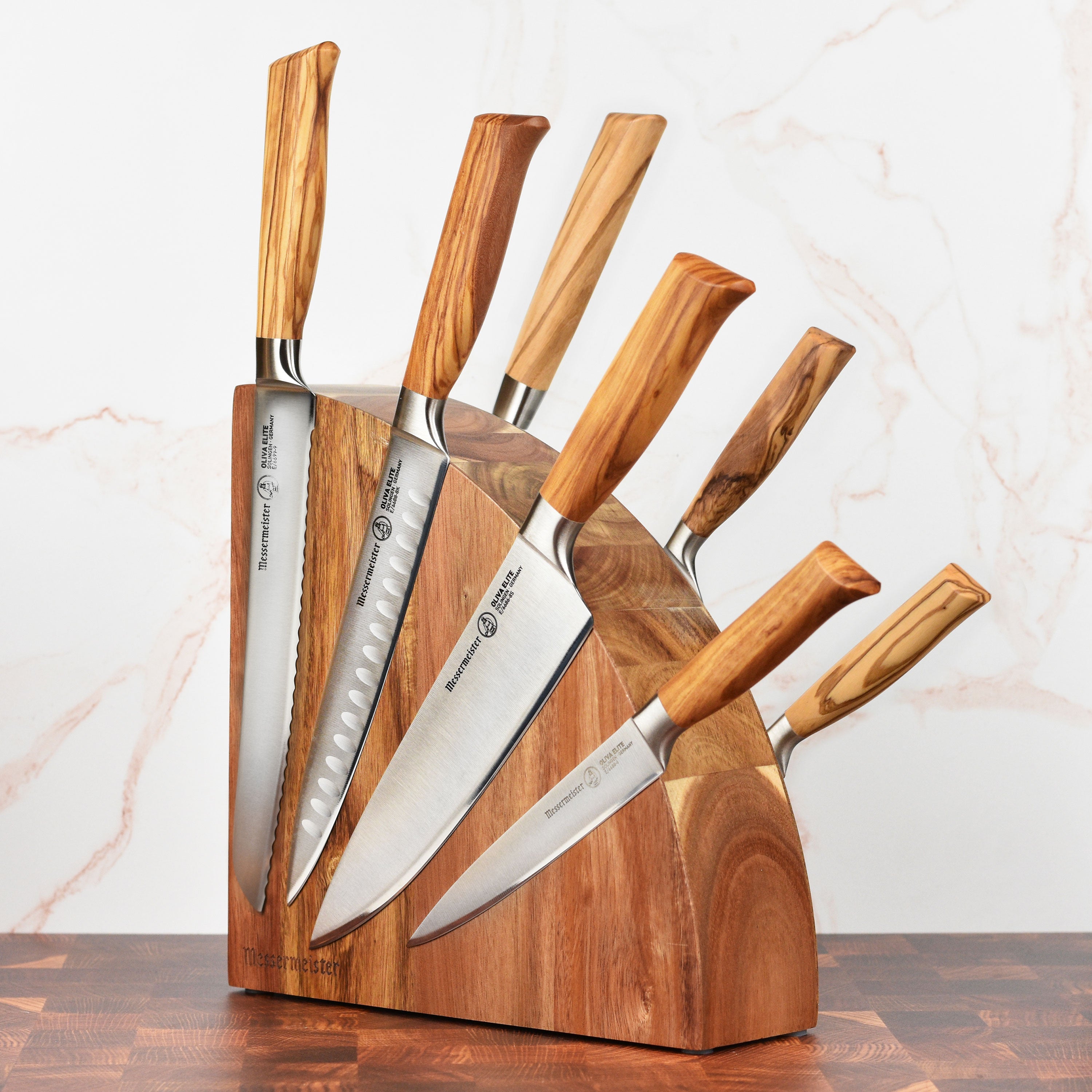 Close-up of German steel chef knives with olive wood handles in a magnetic knife block