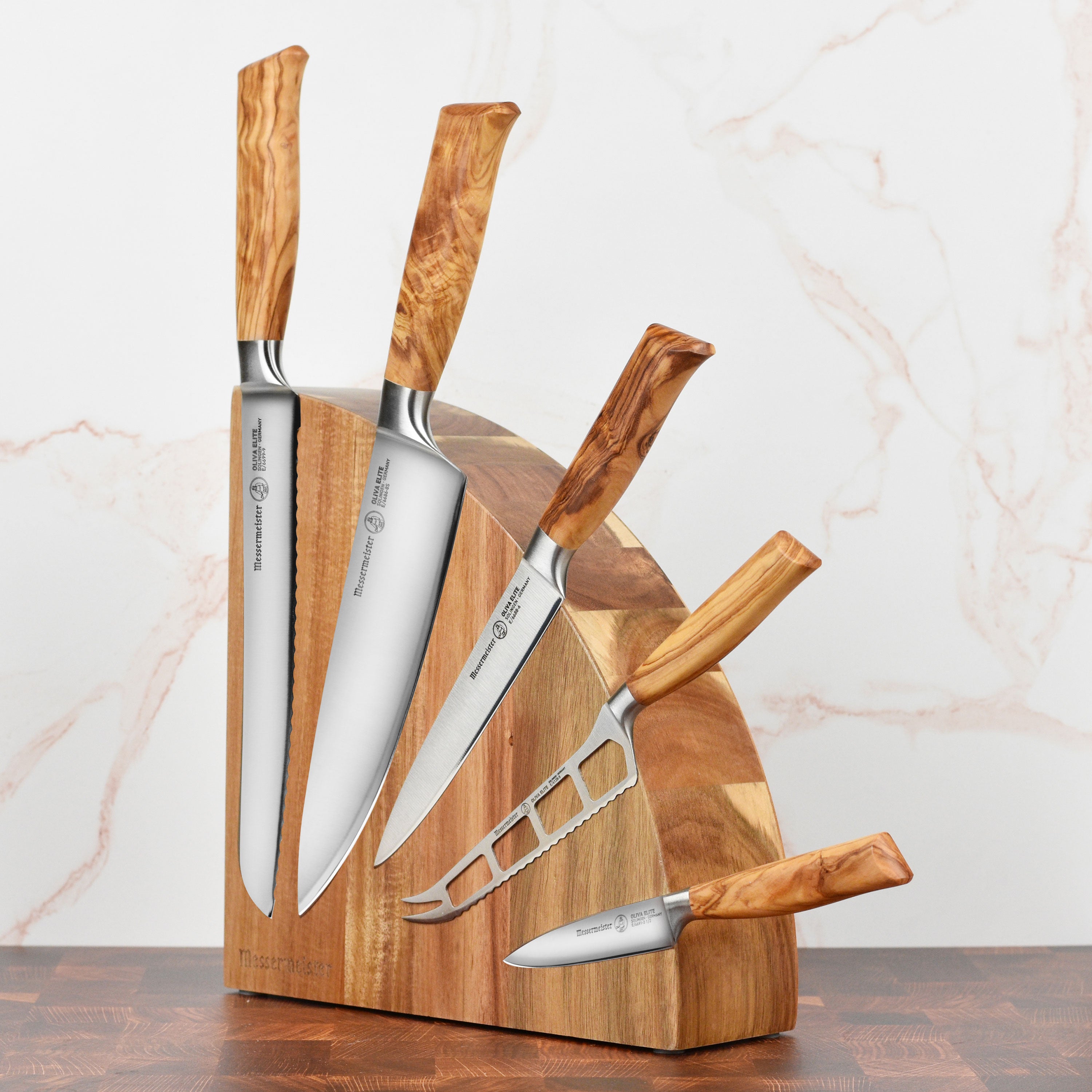 Close-up of forged kitchen knives with olive wood handles on a magnetic knife block