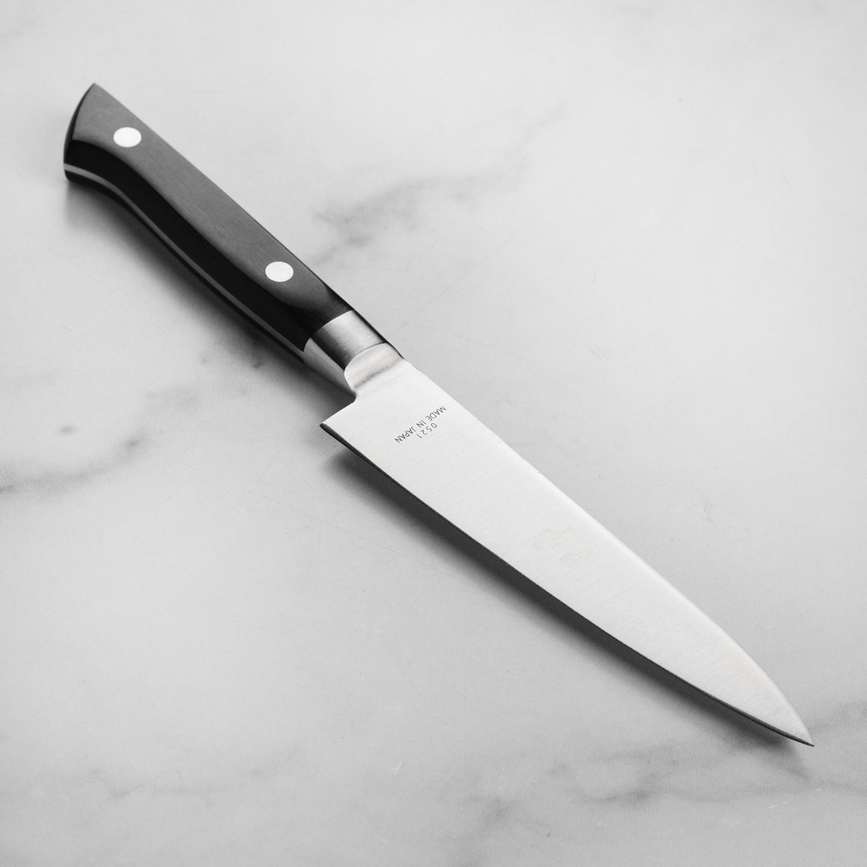Close-up view of the PrecisionCraft utility knife highlighting its high carbon steel blade and Pakkawood handle.