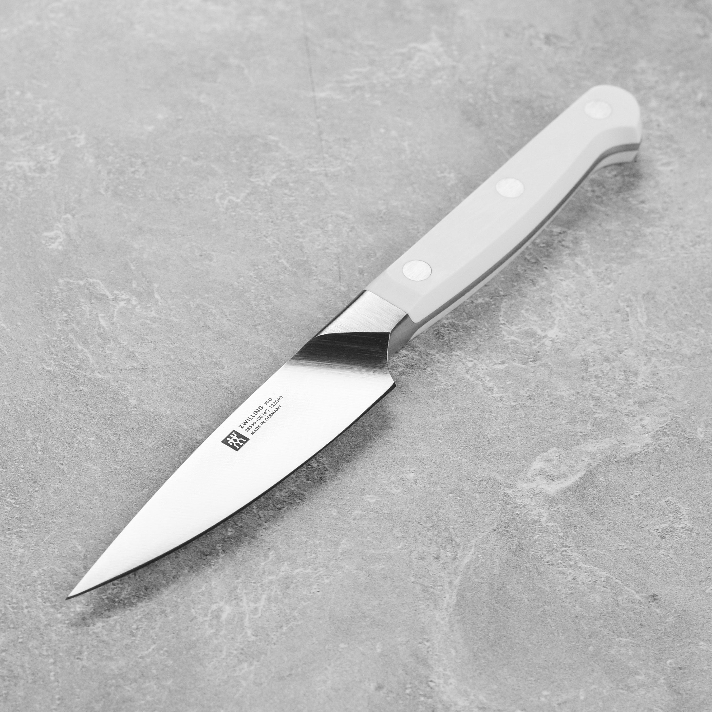 Zwilling Pro Le Blanc paring knife with a precision forged blade, angled for cutting fruits.