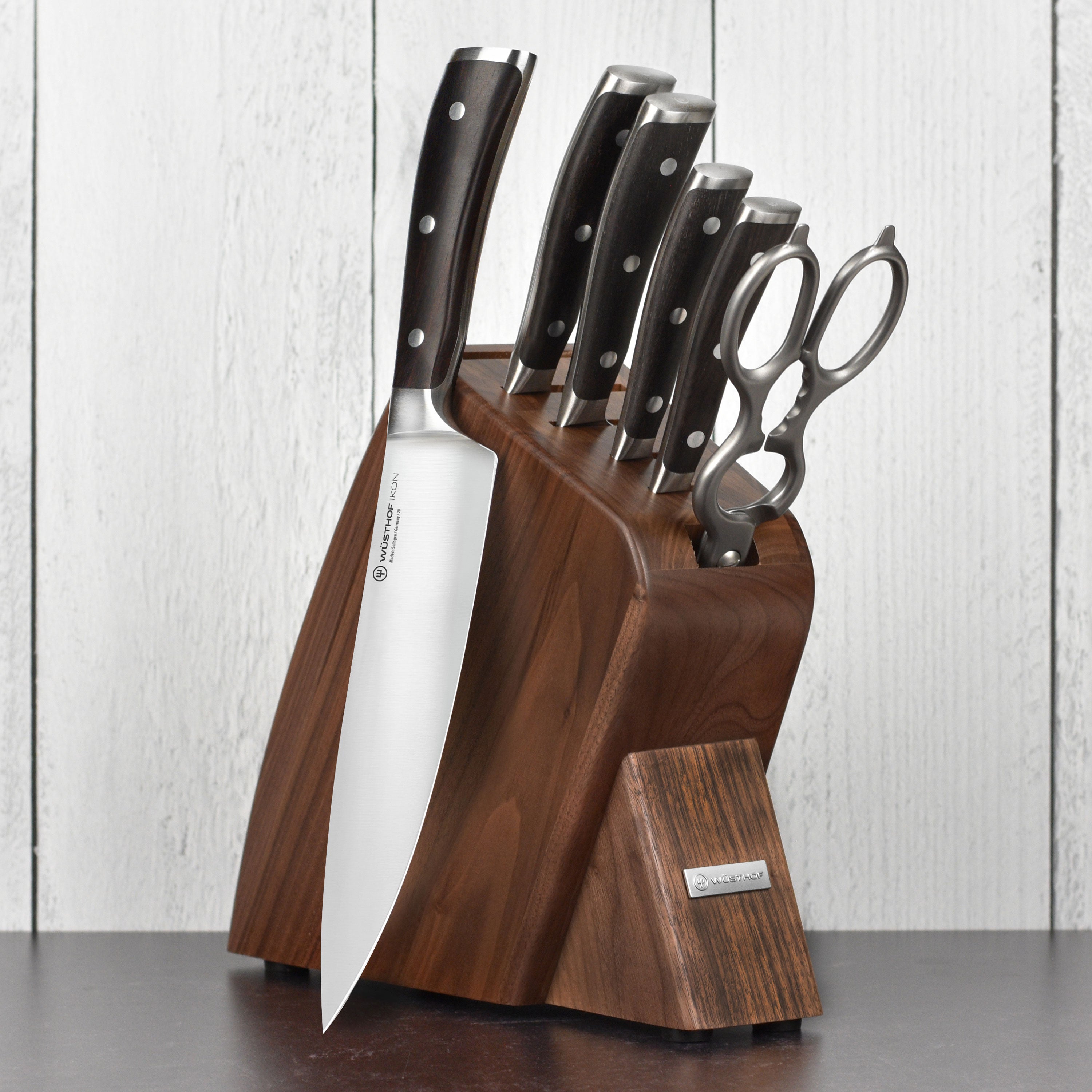 Wusthof Ikon Blackwood knife set showcasing the chef knives in a walnut block from a side angle.