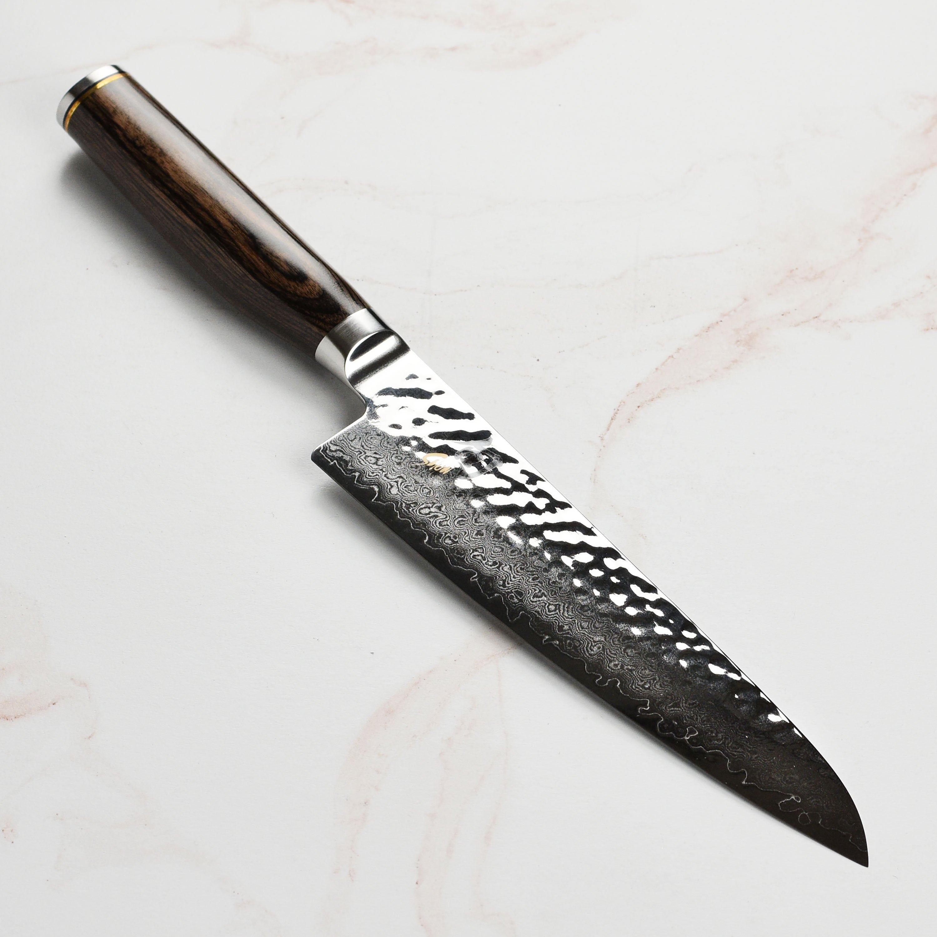 Close-up of Damascus layered chef's knife with hammered finish for precision slicing