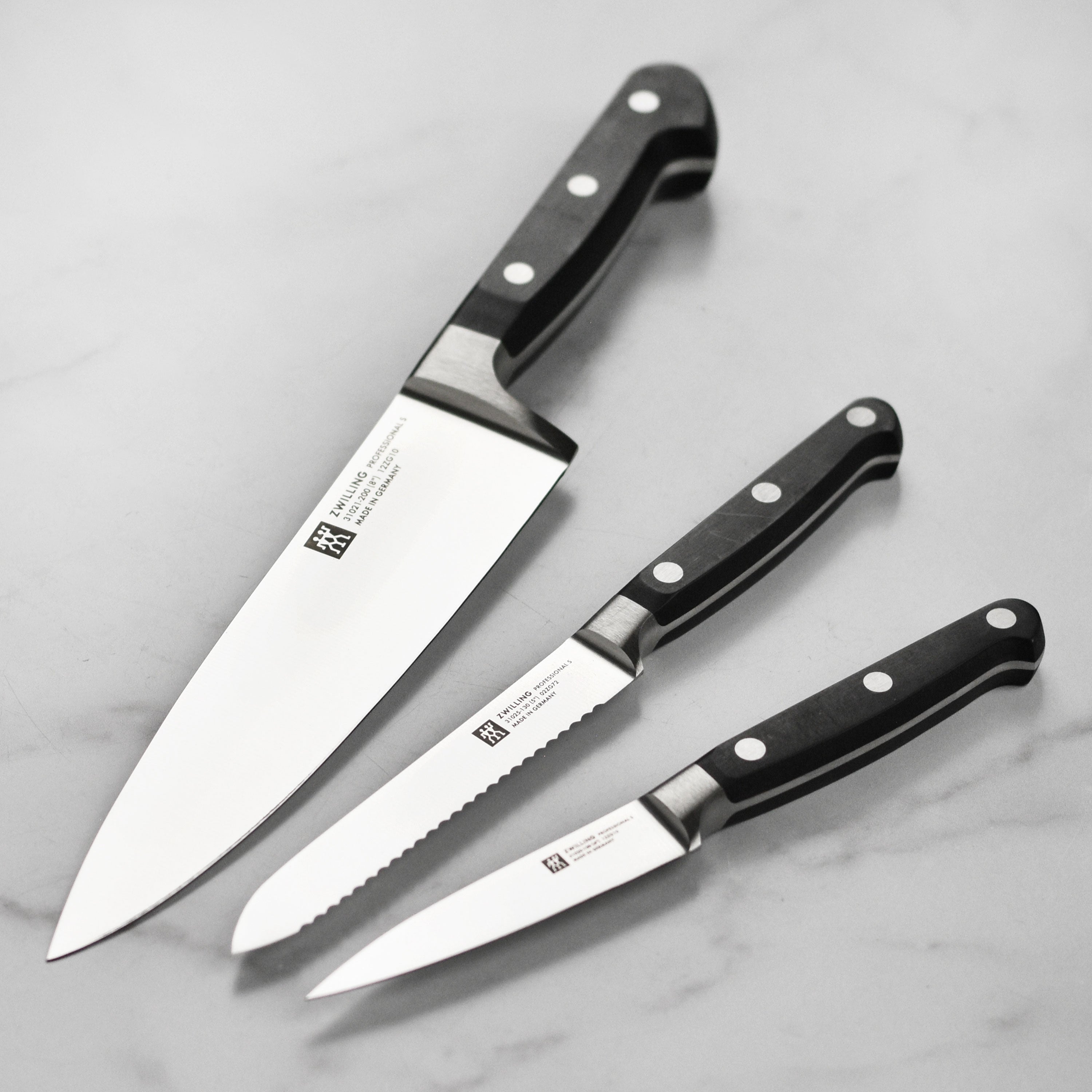 Zwilling Professional Chef Knife Set displayed on a wooden cutting board, showcasing the high carbon stainless steel blades.