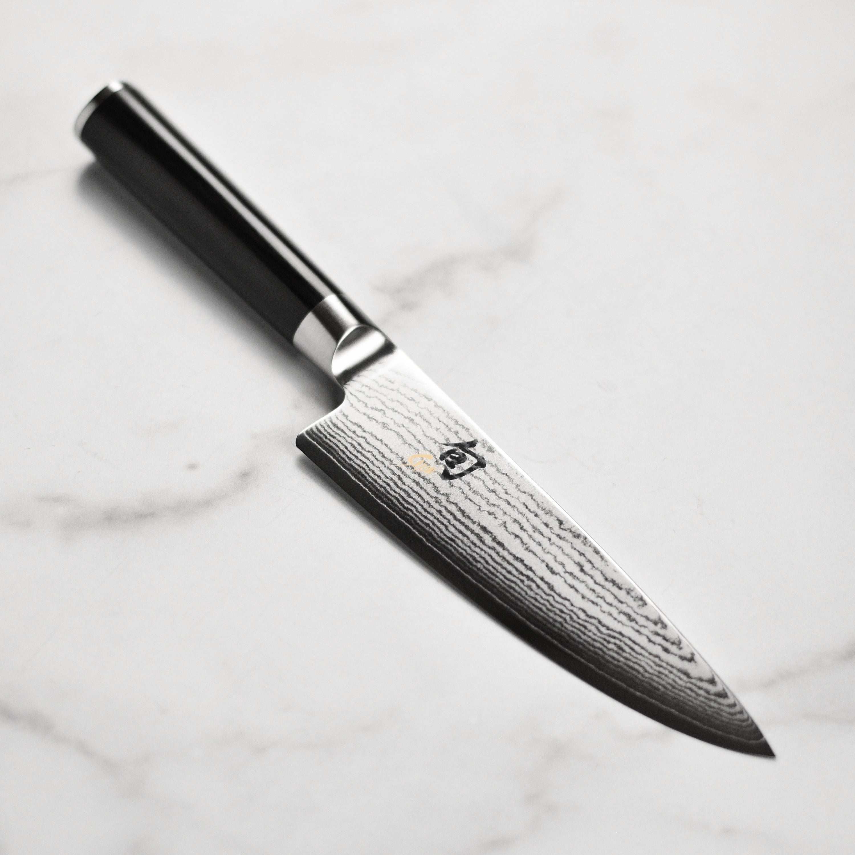 Close-up of the Shun Classic 6-Inch Damascus Chef's Knife showing the intricate blade pattern and sharp edge.