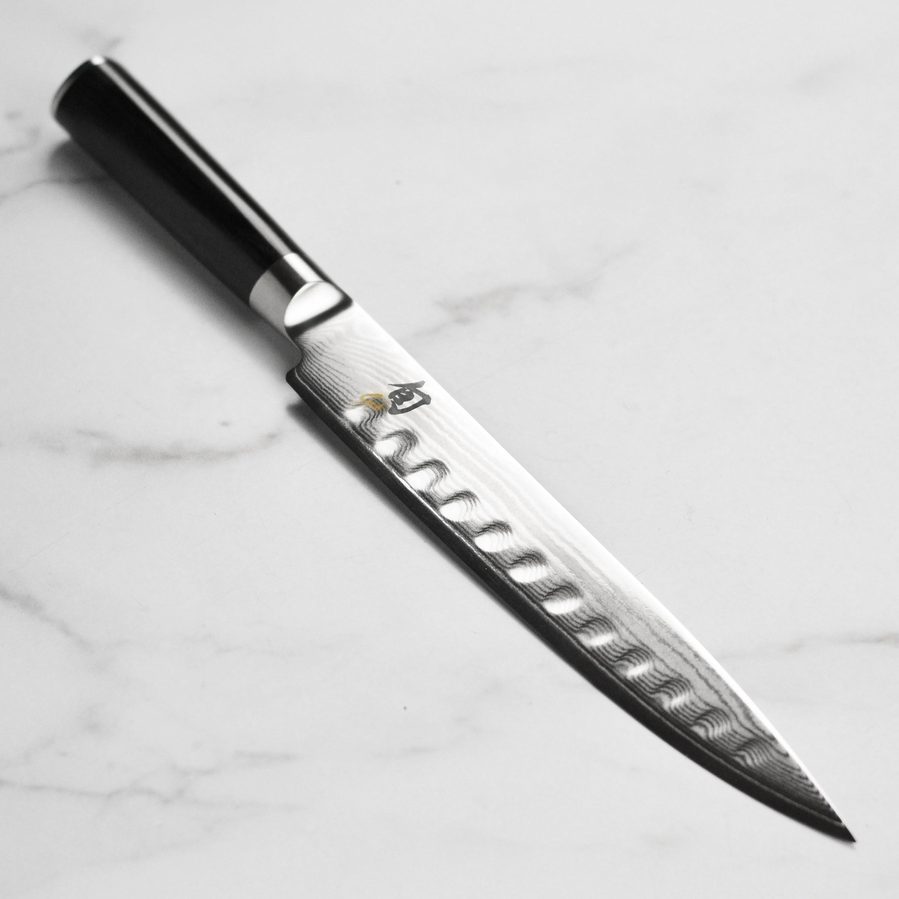 Side profile view of the Shun Classic 9 inch slicing knife with hollow edge, showcasing its Damascus layering.