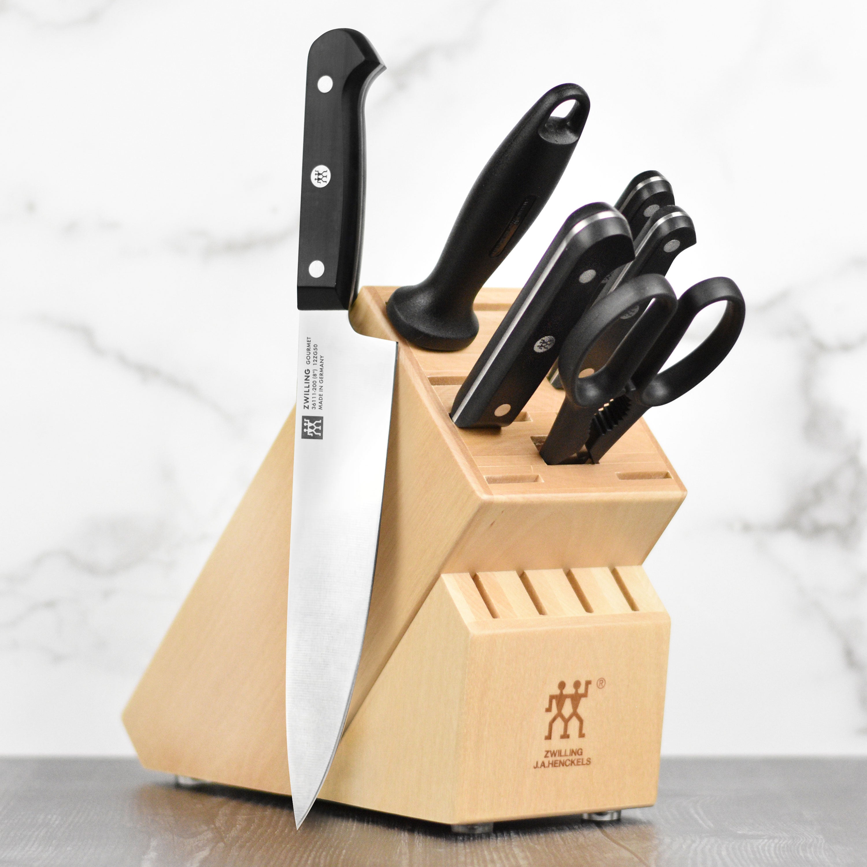 Close-up of Zwilling Gourmet high-carbon stainless steel chef knife set on wooden cutting board.