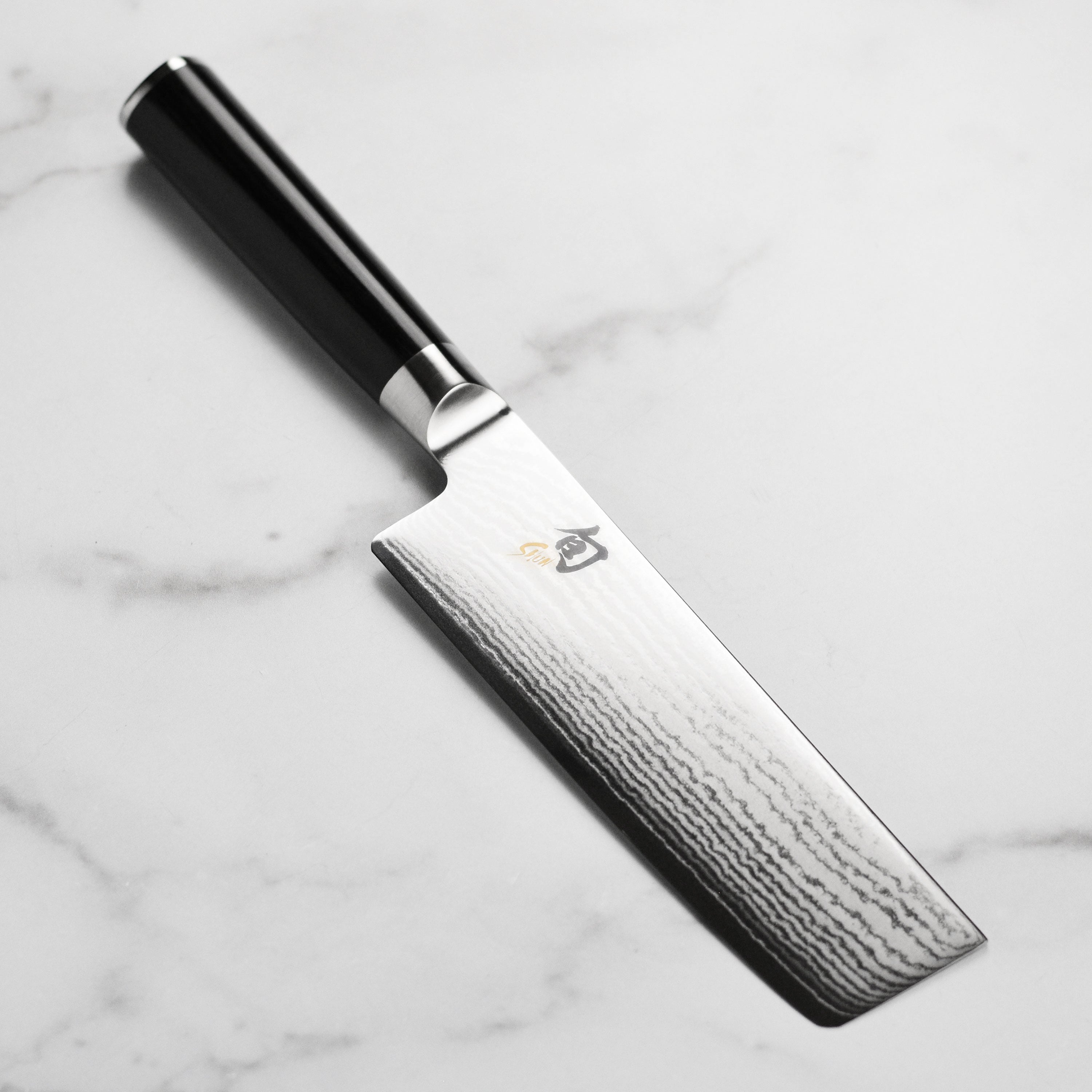 Close-up of Shun knife blade with Damascus pattern highlighting vegetable-slicing precision