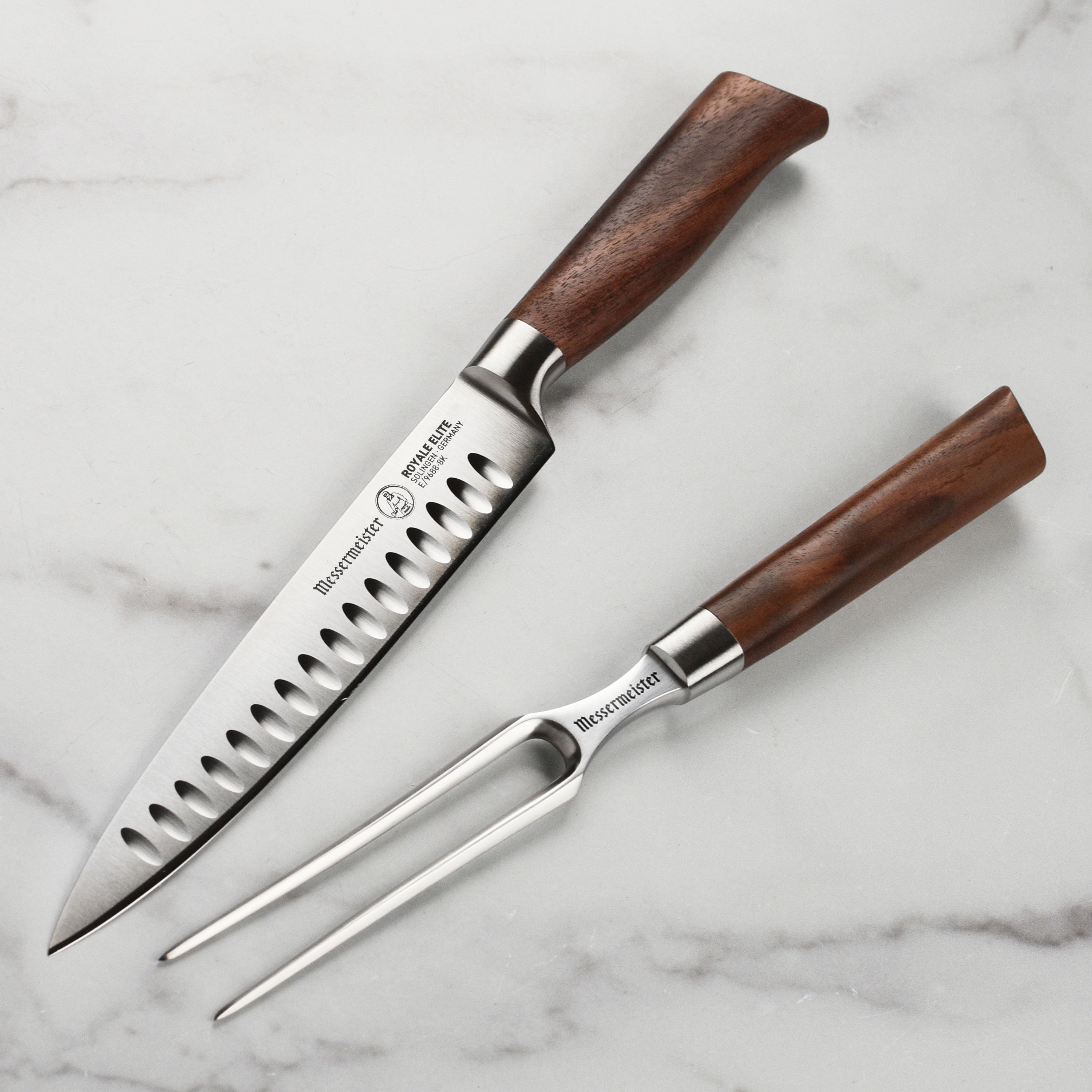 Angled view of the Messermeister Royale Elite carving set with German stainless steel blades on walnut cutting board