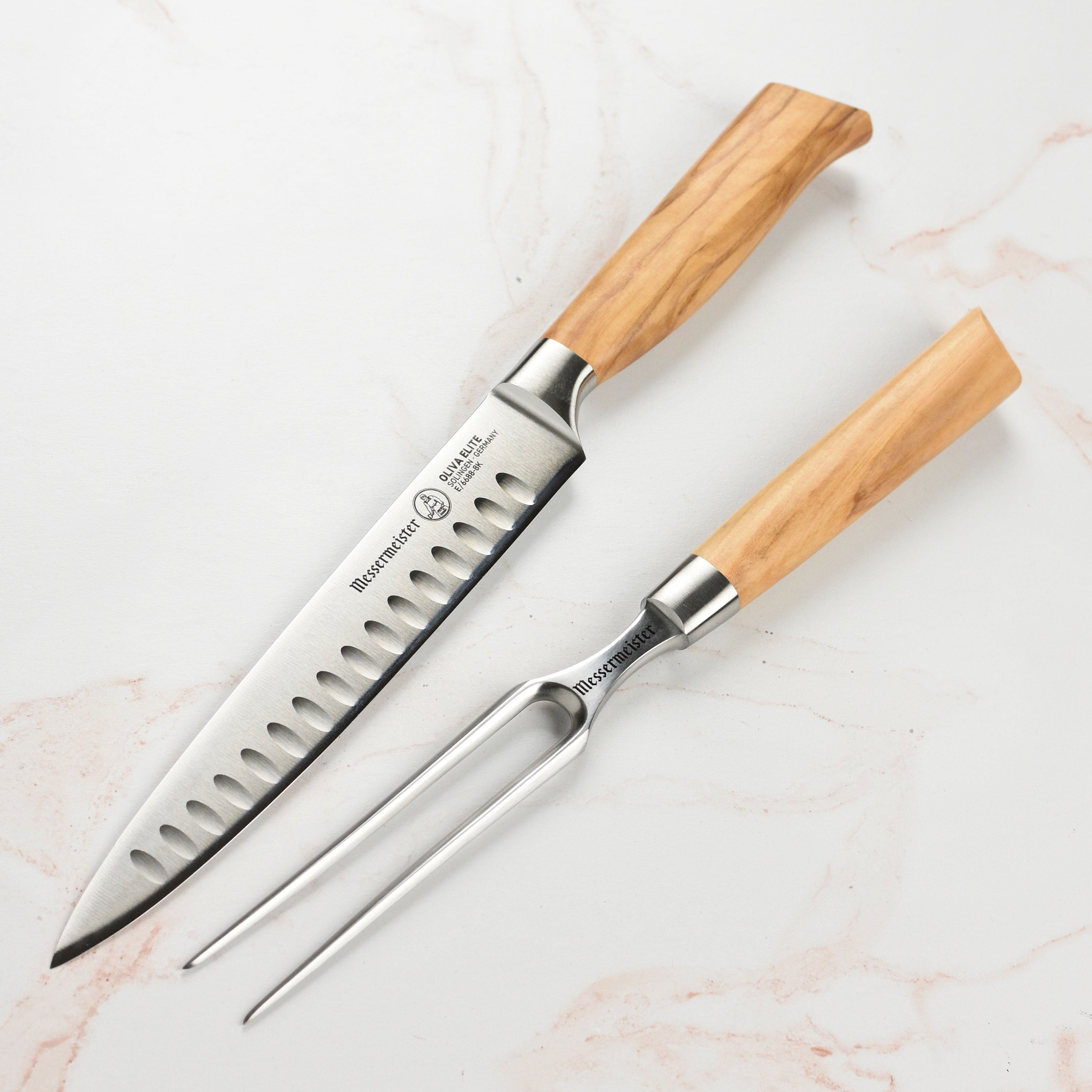 Side view of Messermeister Oliva Elite carving knife and fork on rustic wood surface – ideal carving set for home use.