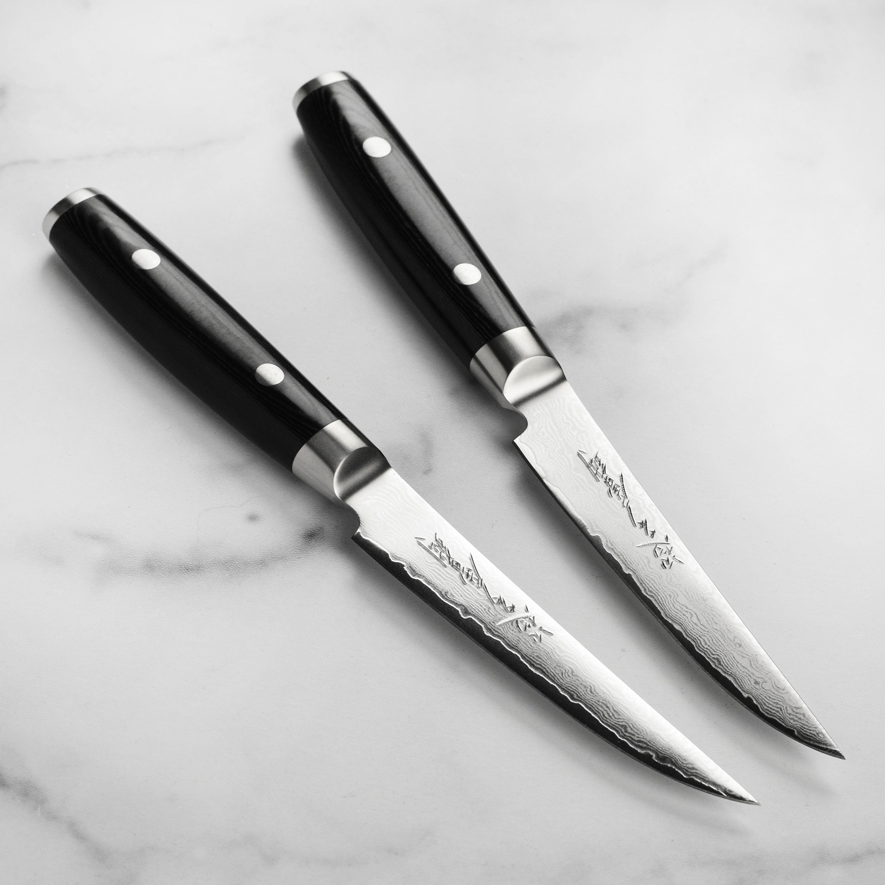 Yaxell Ran Plus steak knife set displayed on a wooden cutting board, highlighting the Damascus pattern.