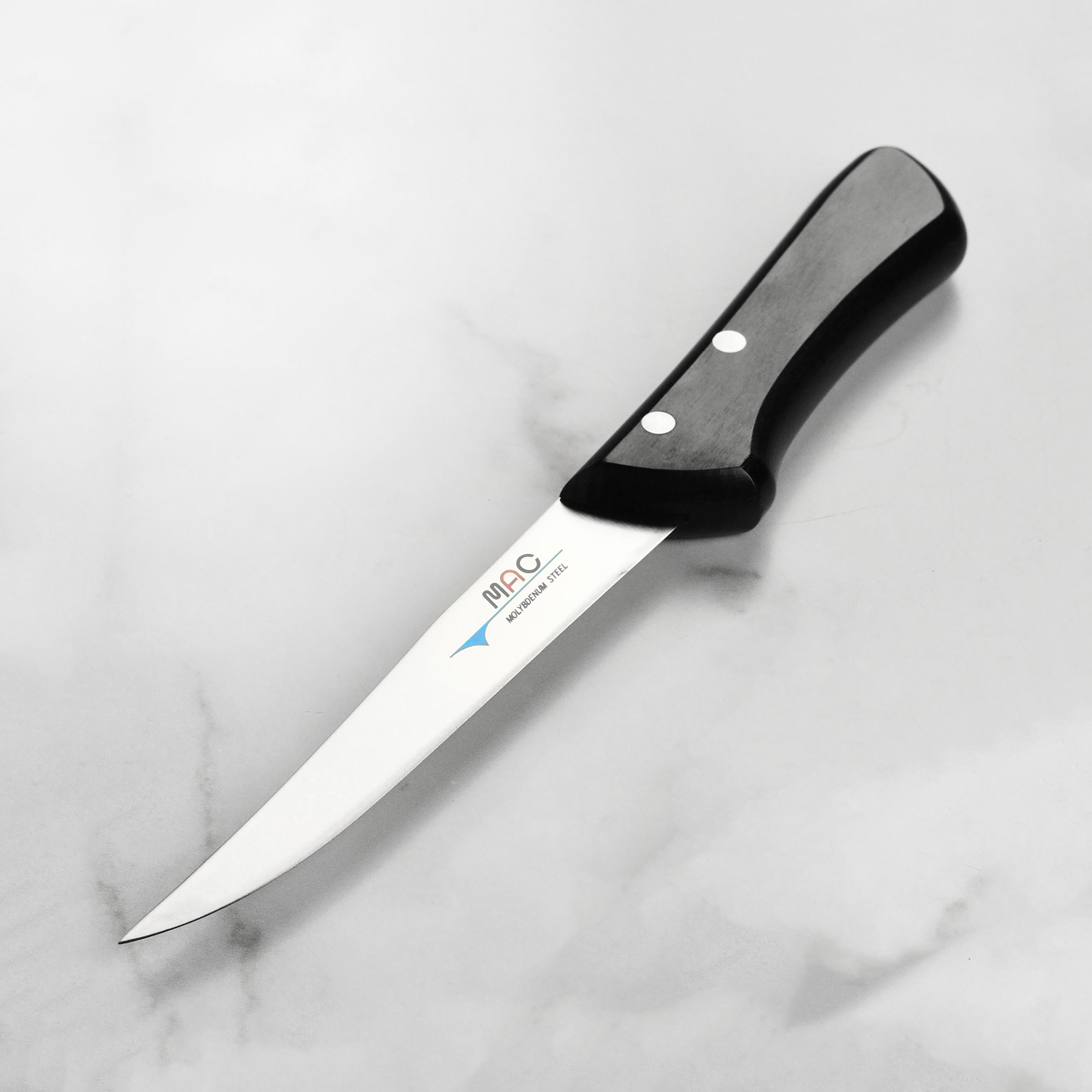 Close-up of the tapered 6-inch boning knife blade slicing through raw salmon with precision