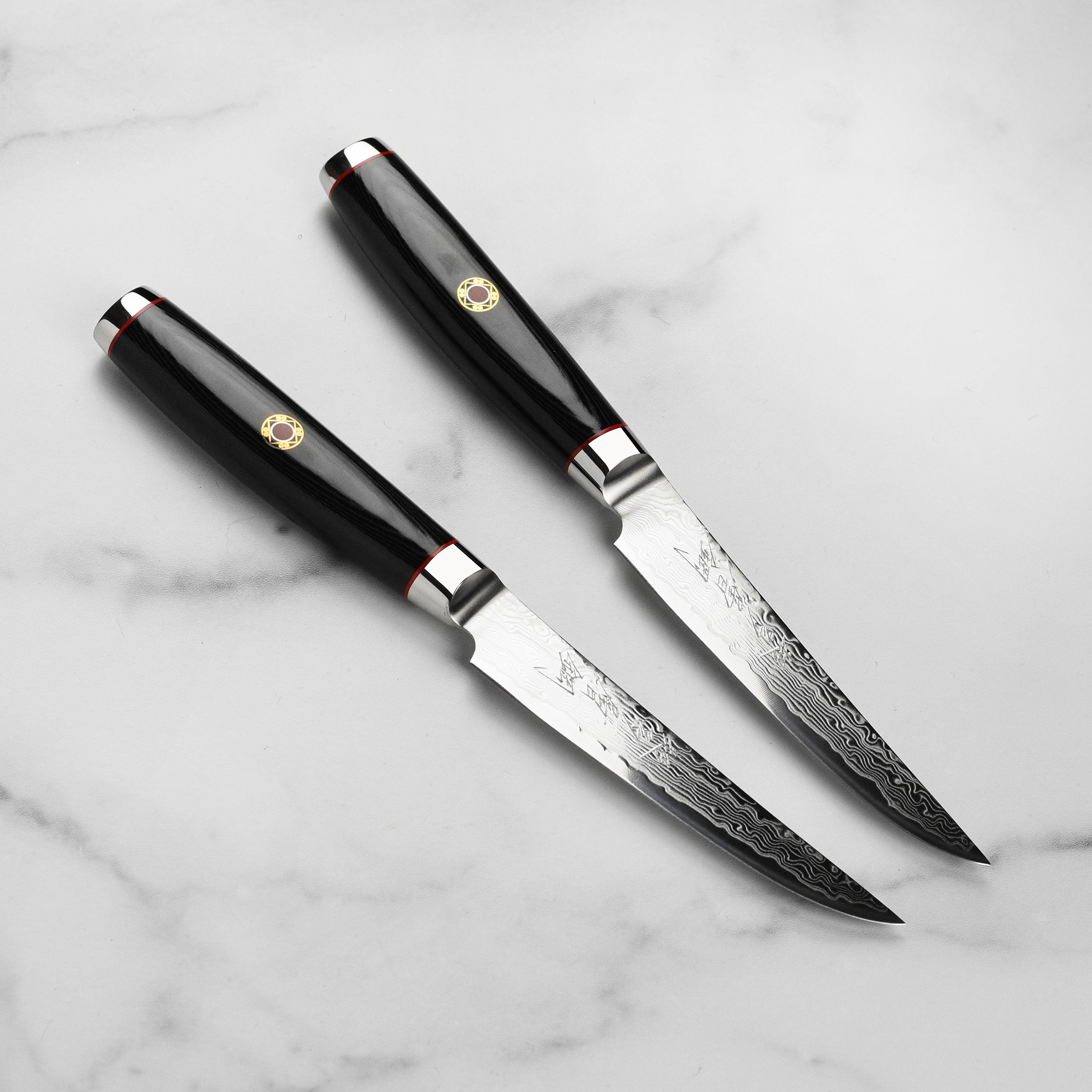 Close-up of Japanese Damascus steak knife with engraved blade and black Micarta handle