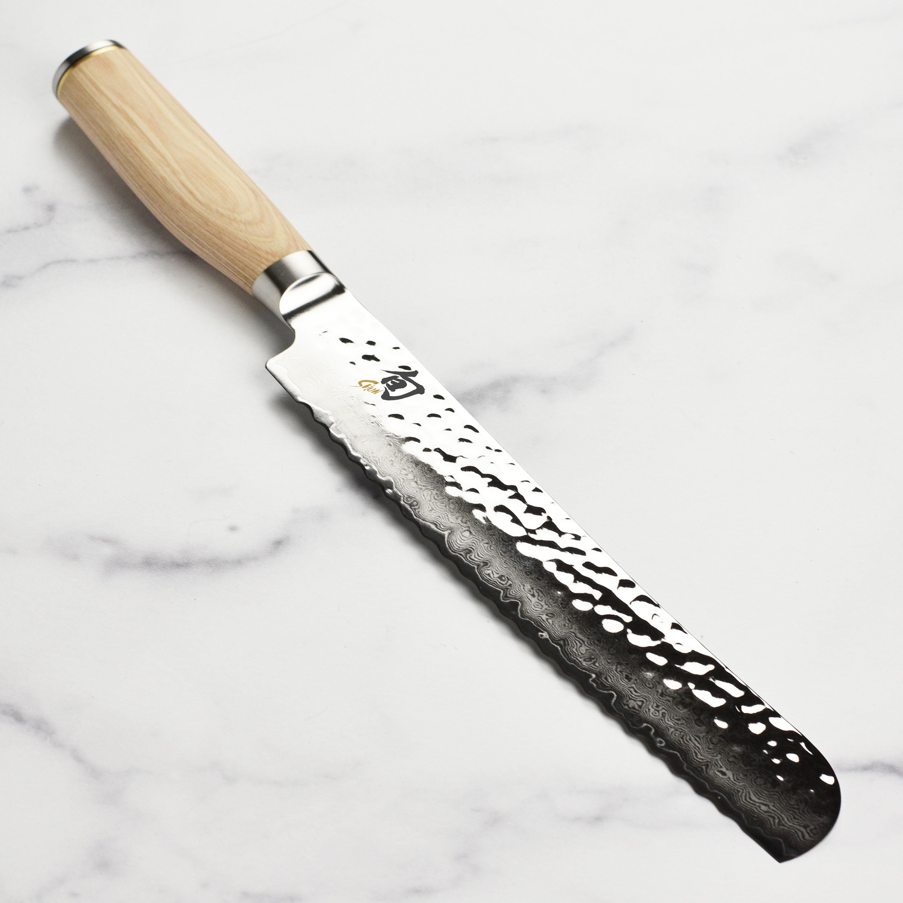 Shun Premier Blonde 9-inch bread knife with Damascus layered blade on a wooden cutting board