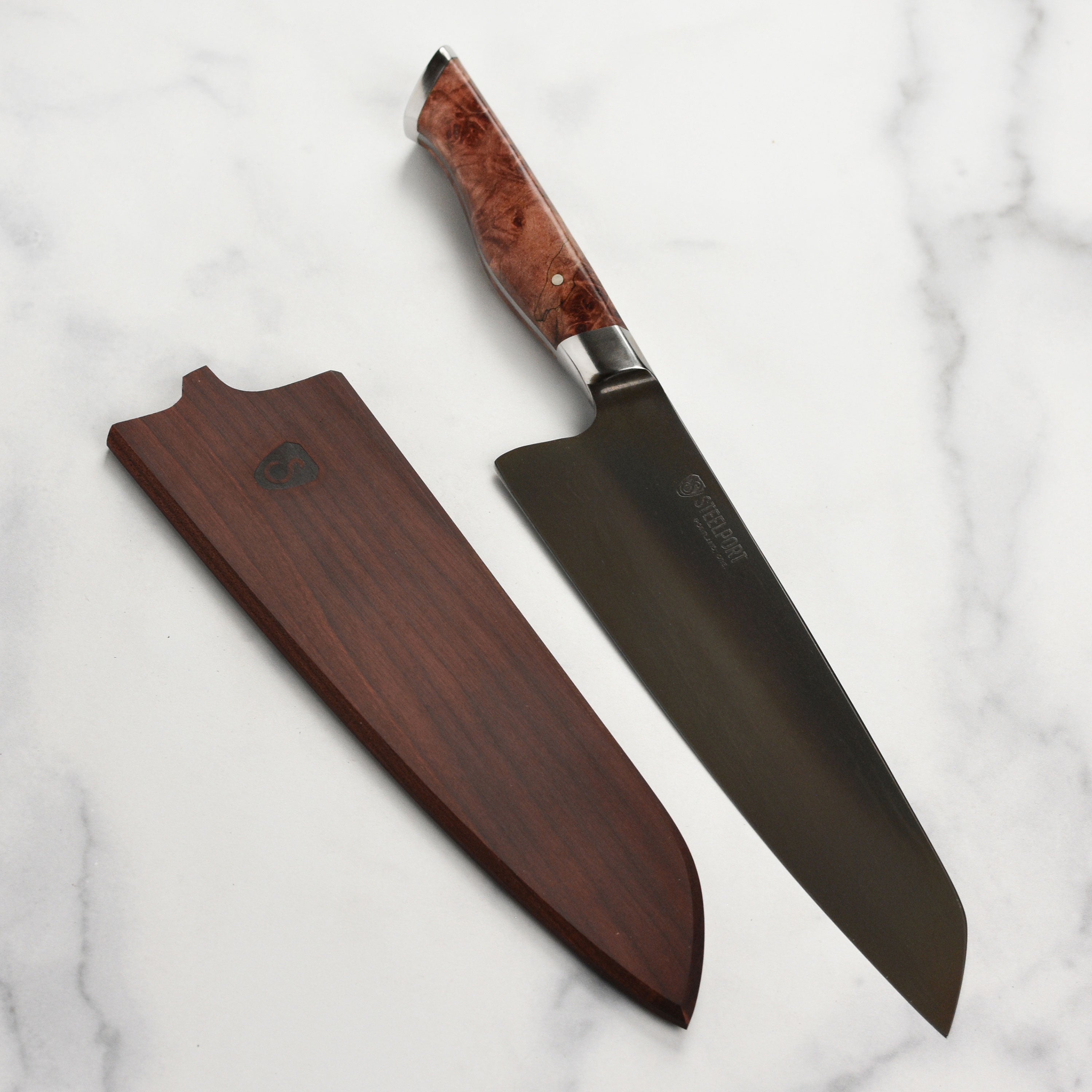 Close-up of the Steelport carbon steel chef's knife with Oregon maple handle, highlighting the craftsmanship and blade sharpness.