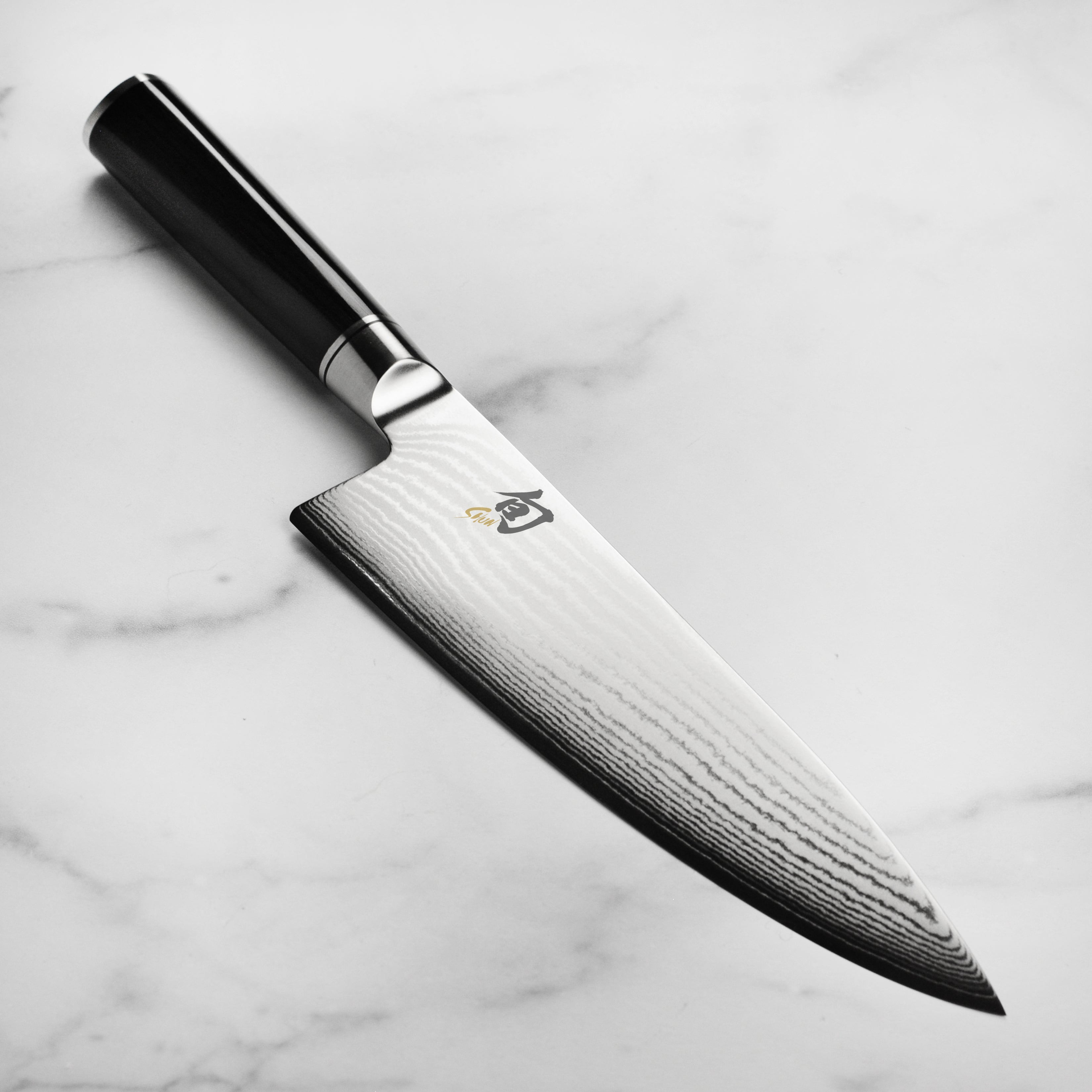 Close-up of Shun Classic 8-inch chef knife, highlighting the VG-MAX steel blade and Damascus pattern.