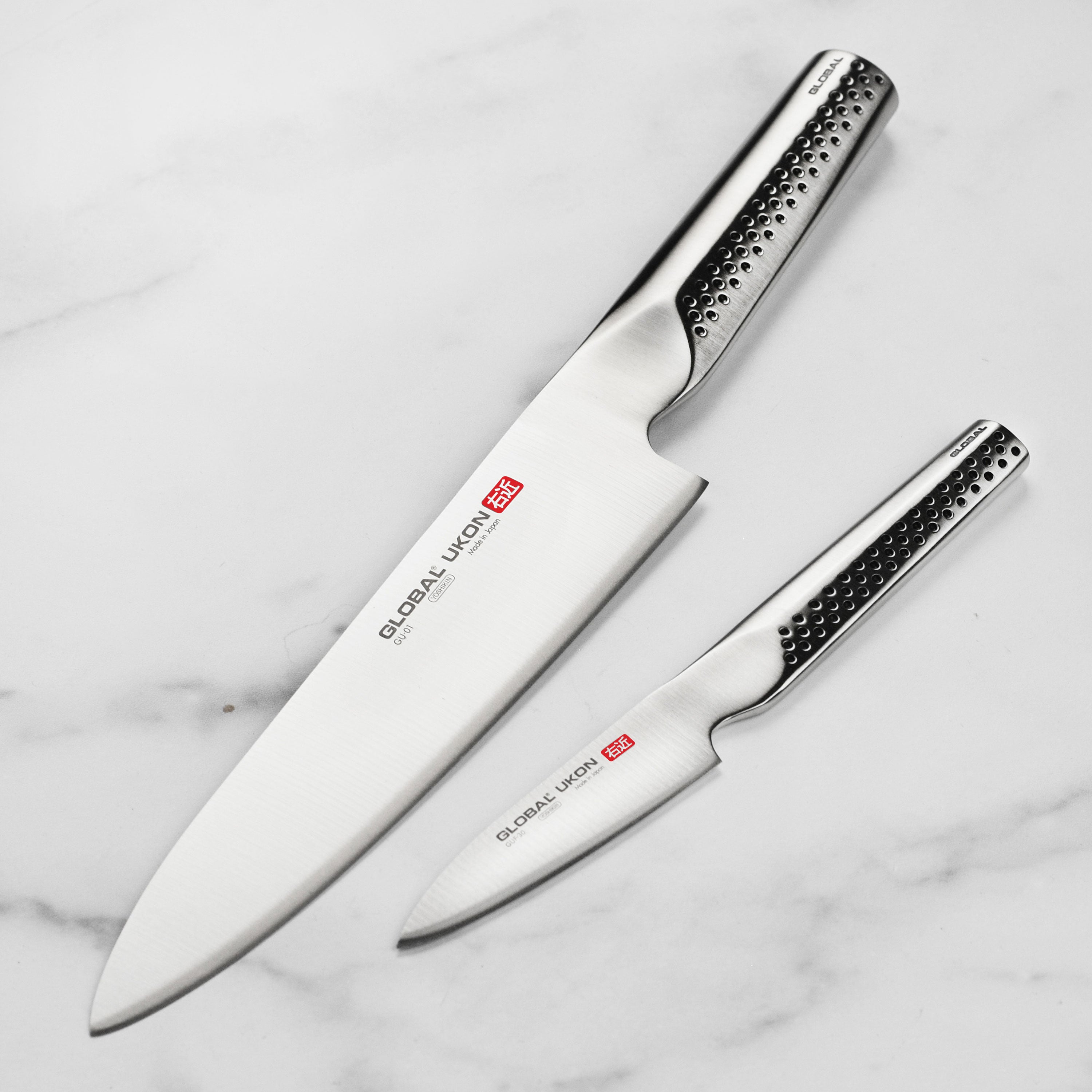 Top view of Global Ukon chef knife resting on cutting board with fresh vegetables
