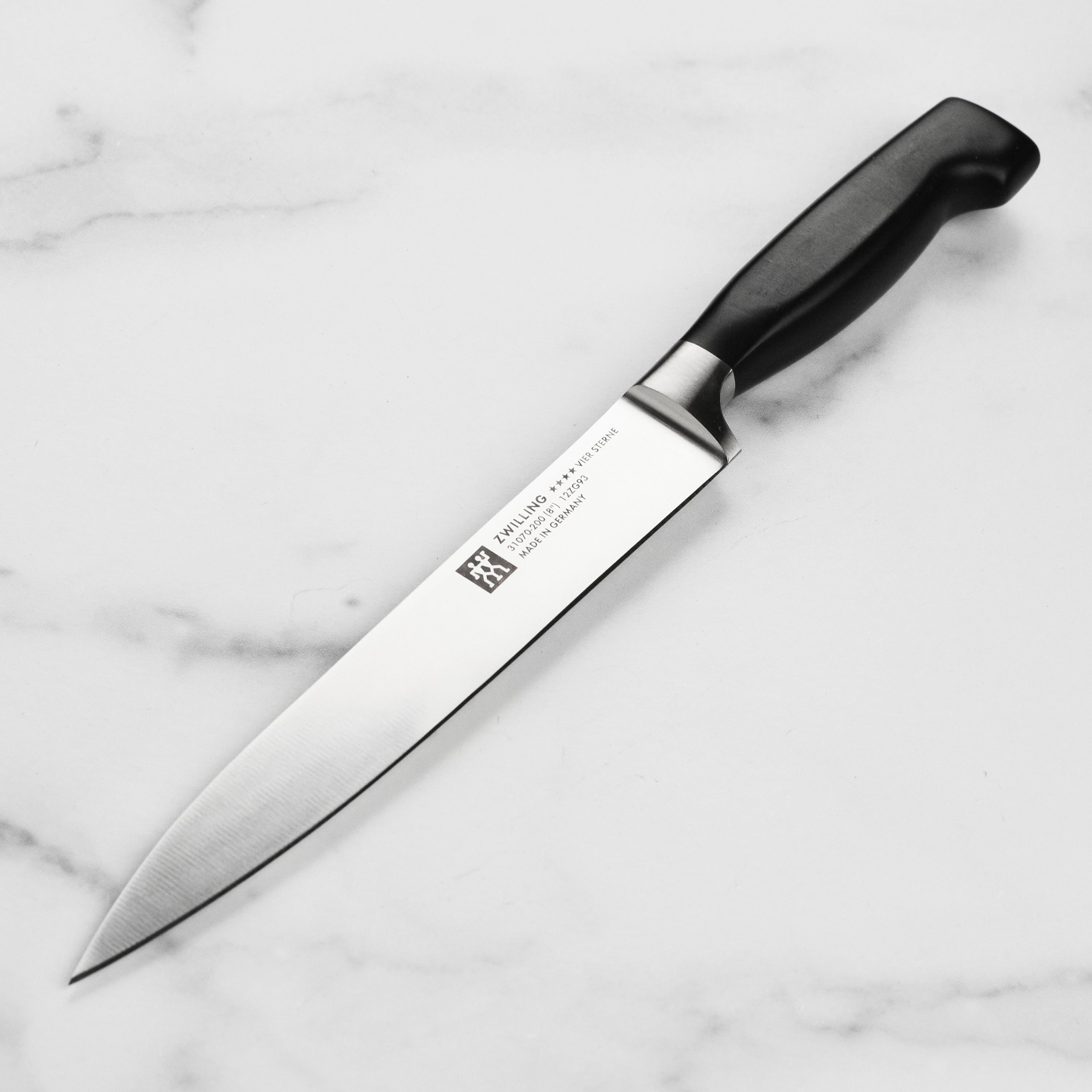 Close-up of Zwilling Four Star 8-Inch carving knife showcasing its sharp blade and ergonomic handle.
