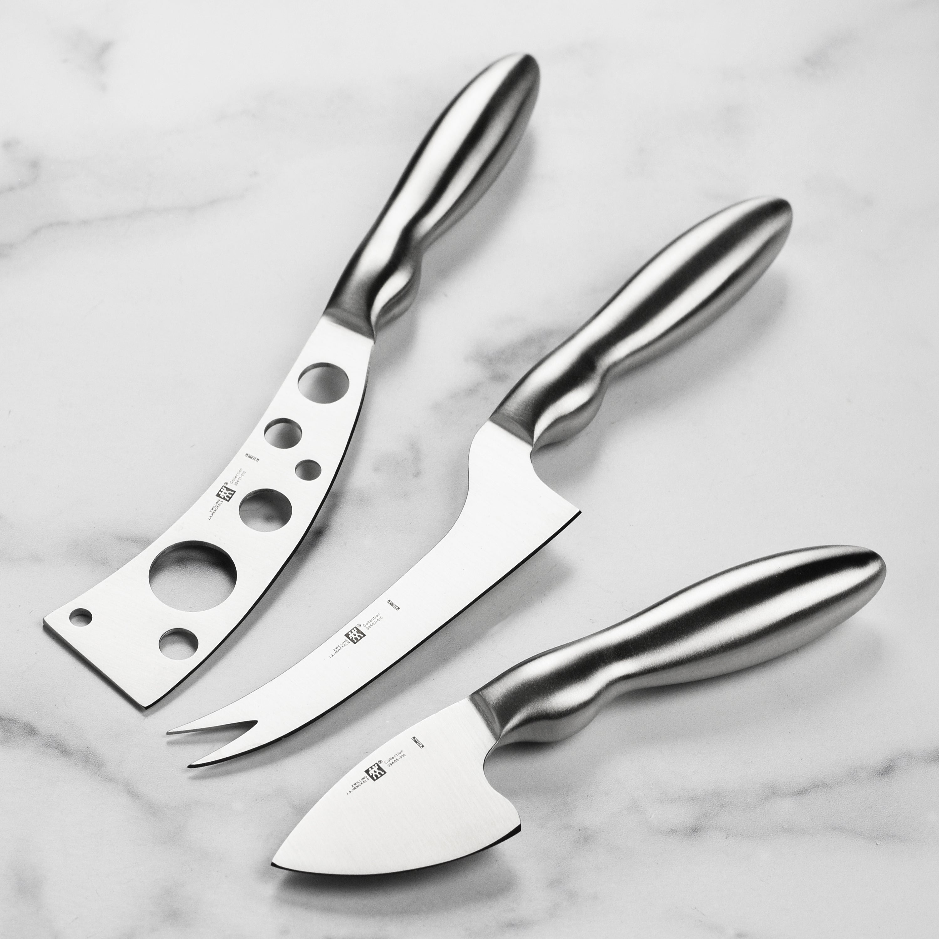 Ergonomic stainless steel cheese knife set displayed on a wooden cheese board, showcasing its sleek design.