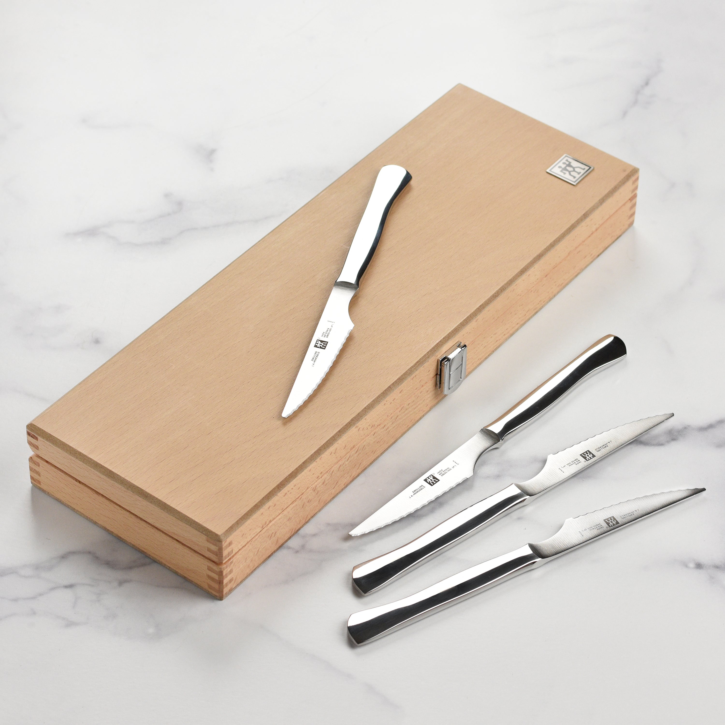 Set of Zwilling stainless steel serrated steak knives arranged in a case