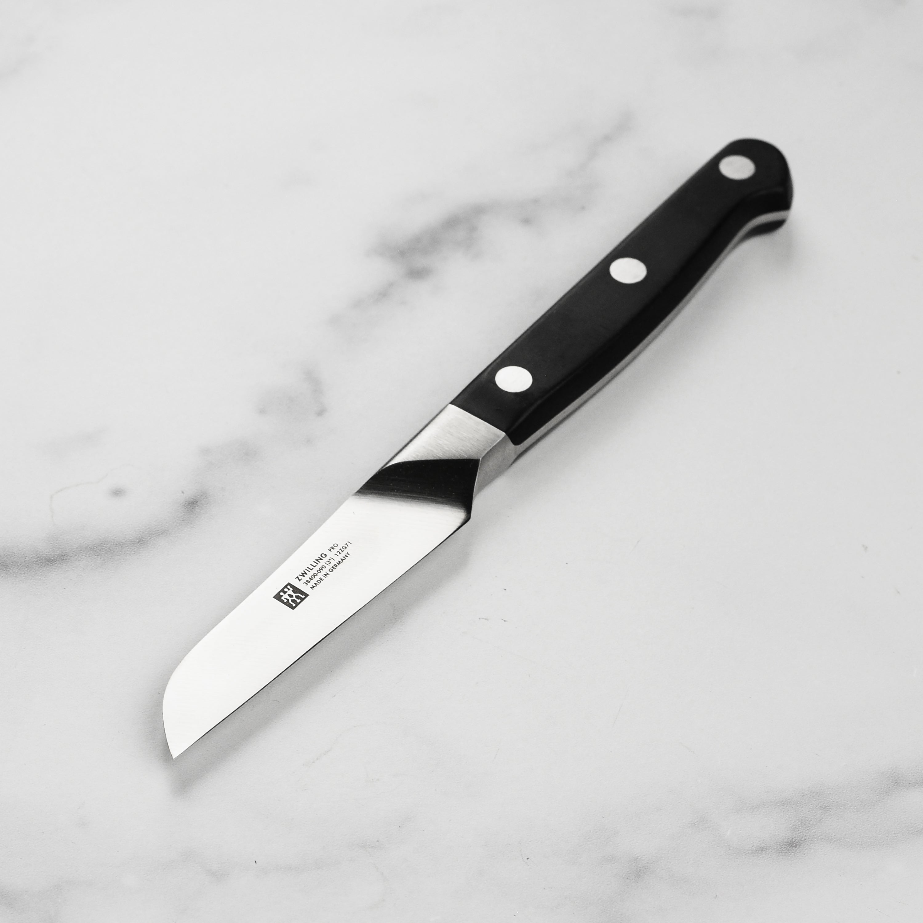 Close-up view of the Zwilling Pro 3-inch high carbon paring knife, highlighting the sharp blade and ergonomic handle.