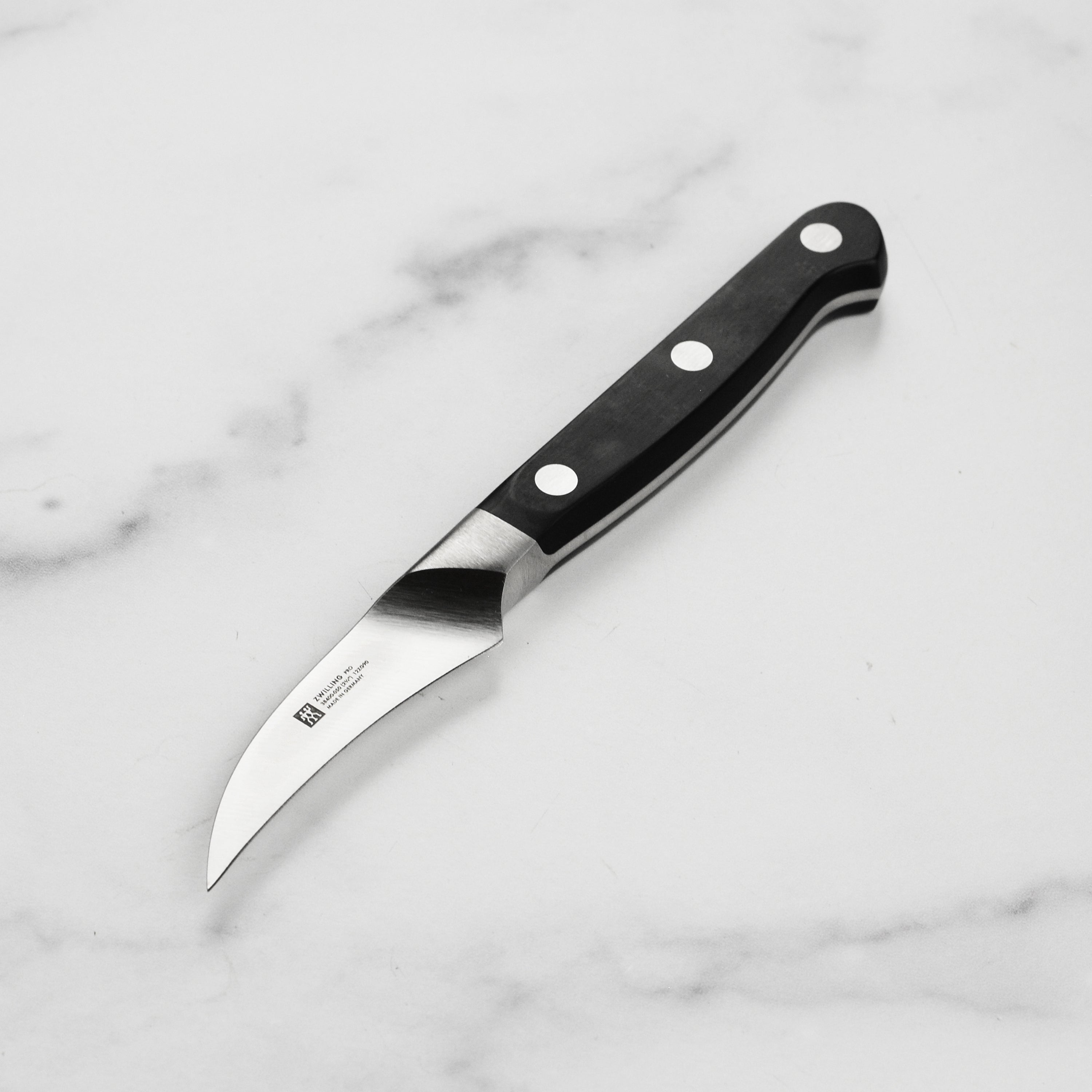 Zwilling Pro peeling knife in hand showing curved blade for vegetable peeling