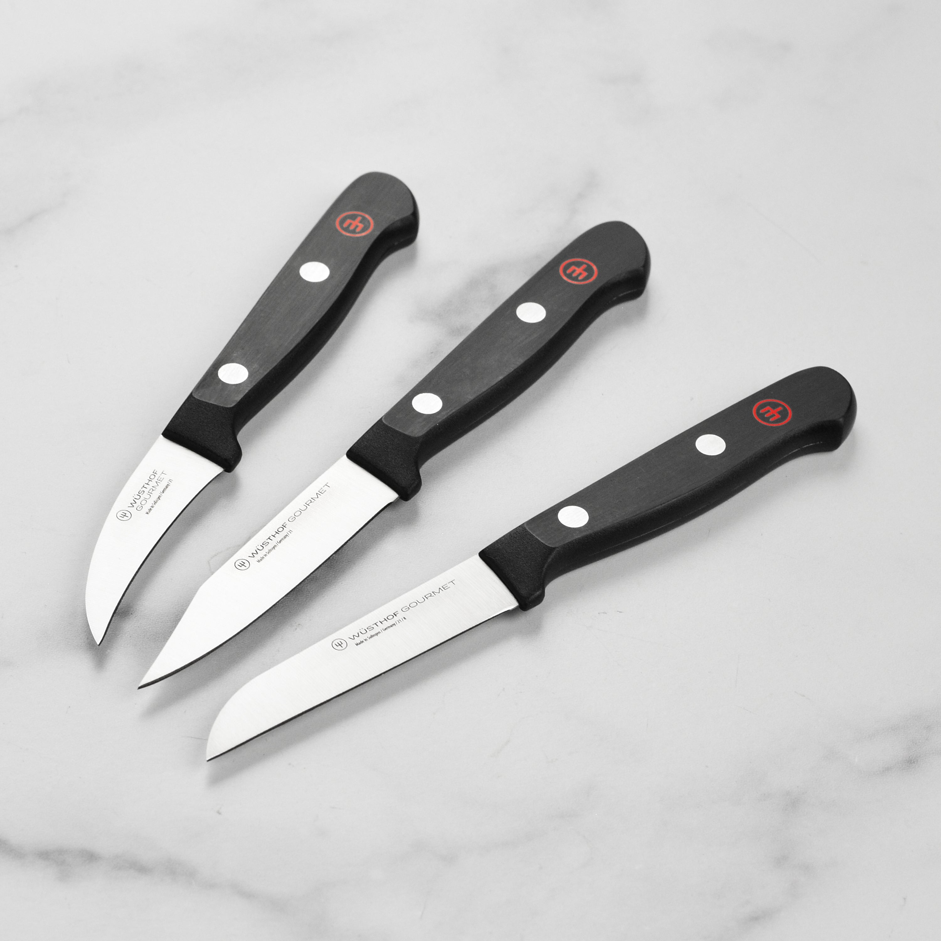 A top-down view of the 3-piece Wusthof paring knife set arranged on a cutting board, ideal for showcasing kitchen knives for professional prep tasks.