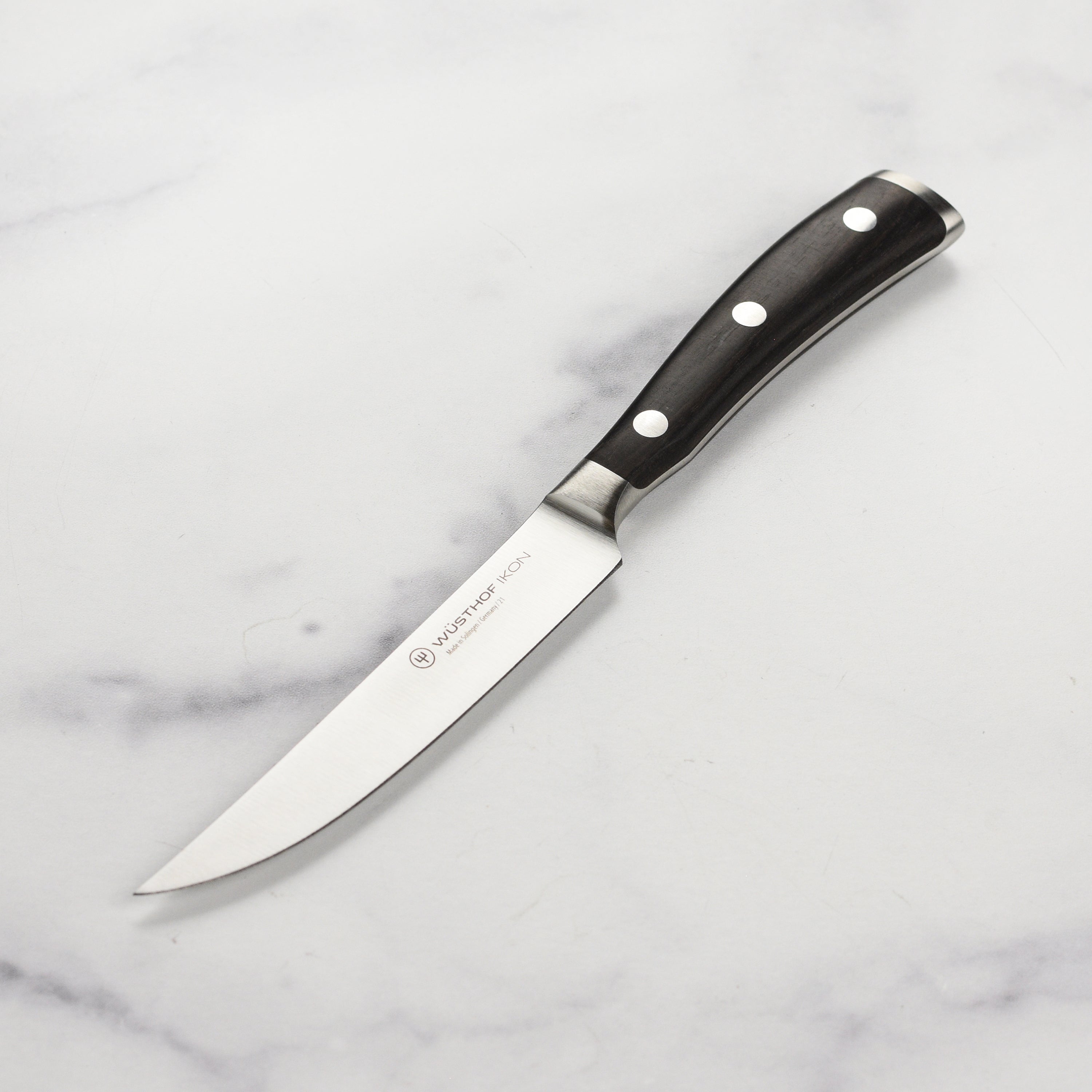Wusthof Ikon steak knife showing the sharp blade for meat slicing.