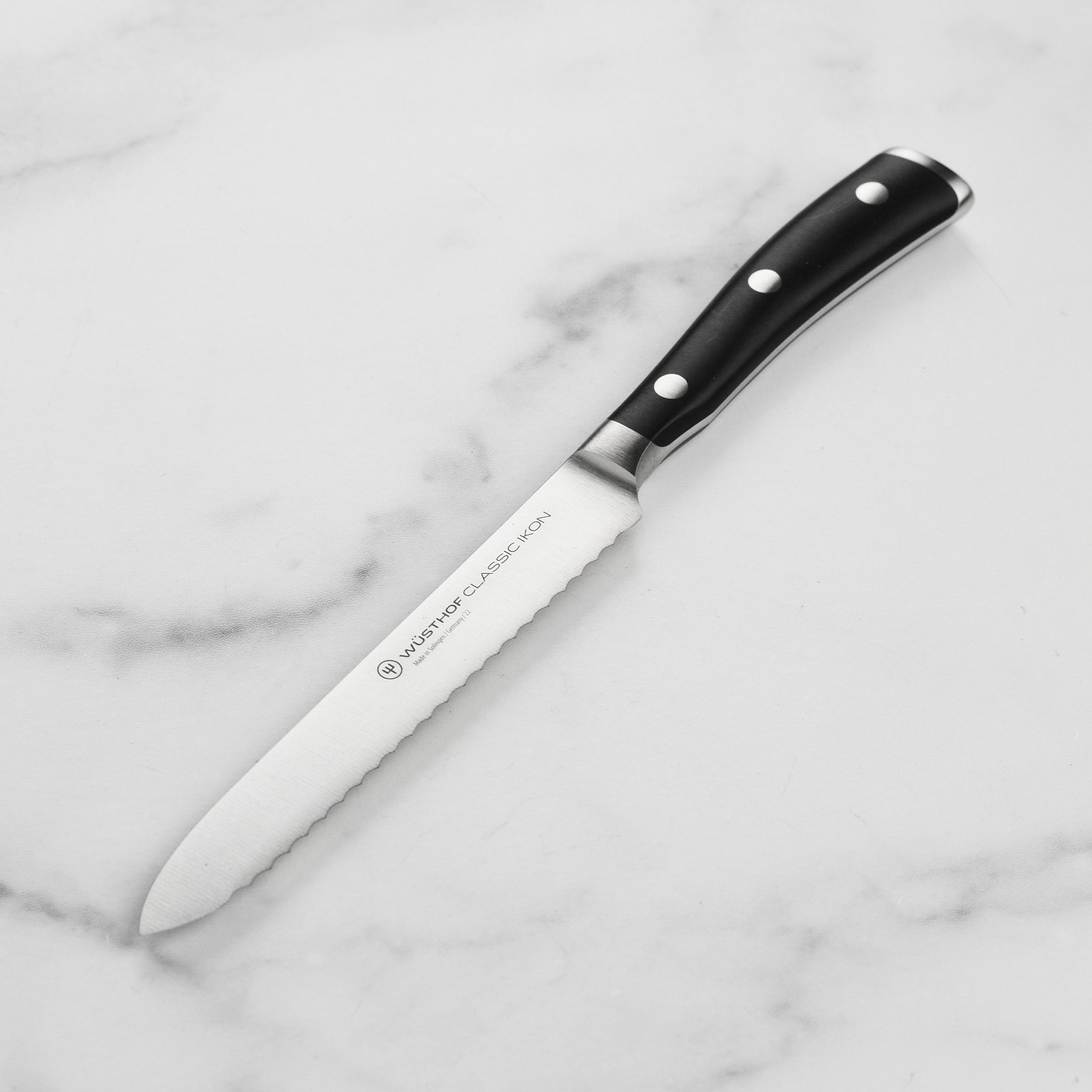 Wusthof Classic Ikon 5-inch serrated utility knife showcasing its precision edge and ergonomic handle.
