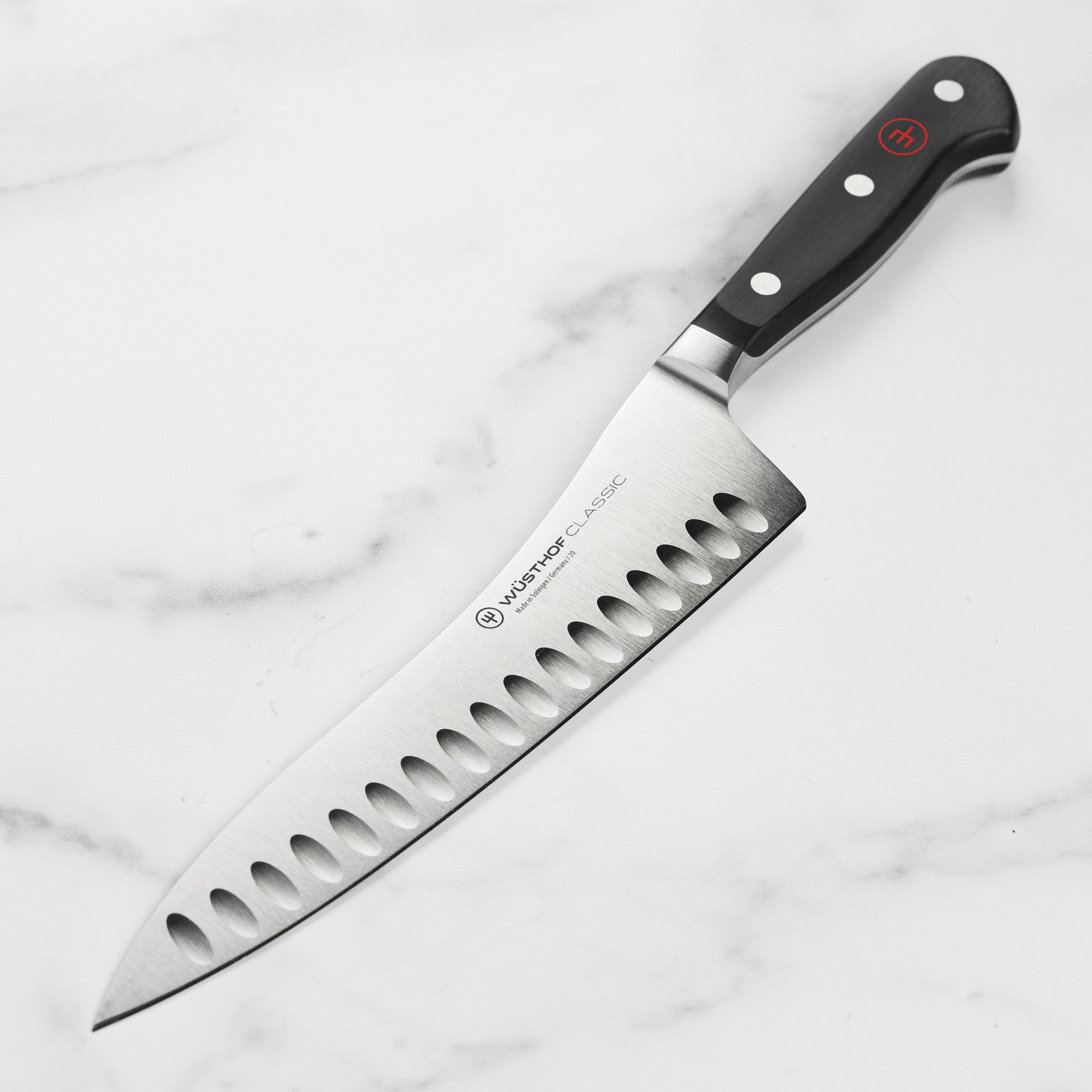 Wusthof Classic 8 Inch Hollow Edge Chef Knife on a wooden cutting board, highlighting its sharp blade and ergonomic handle.