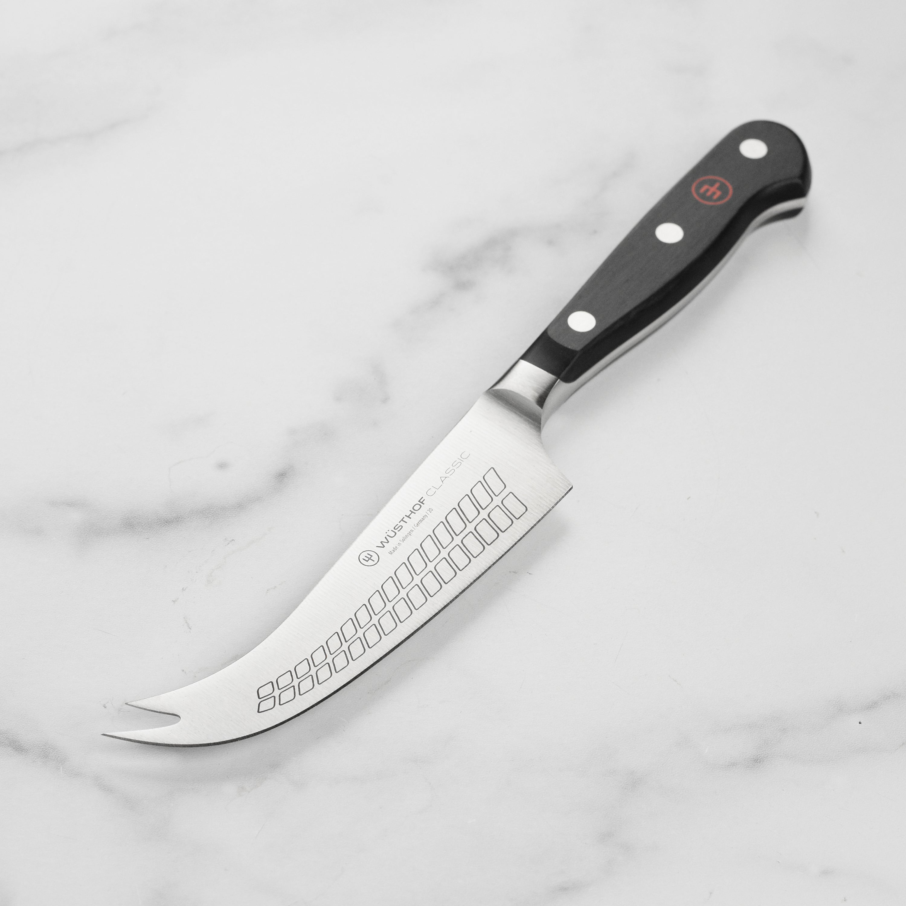Wusthof classic cheese knife slicing hard cheese on a cheese board