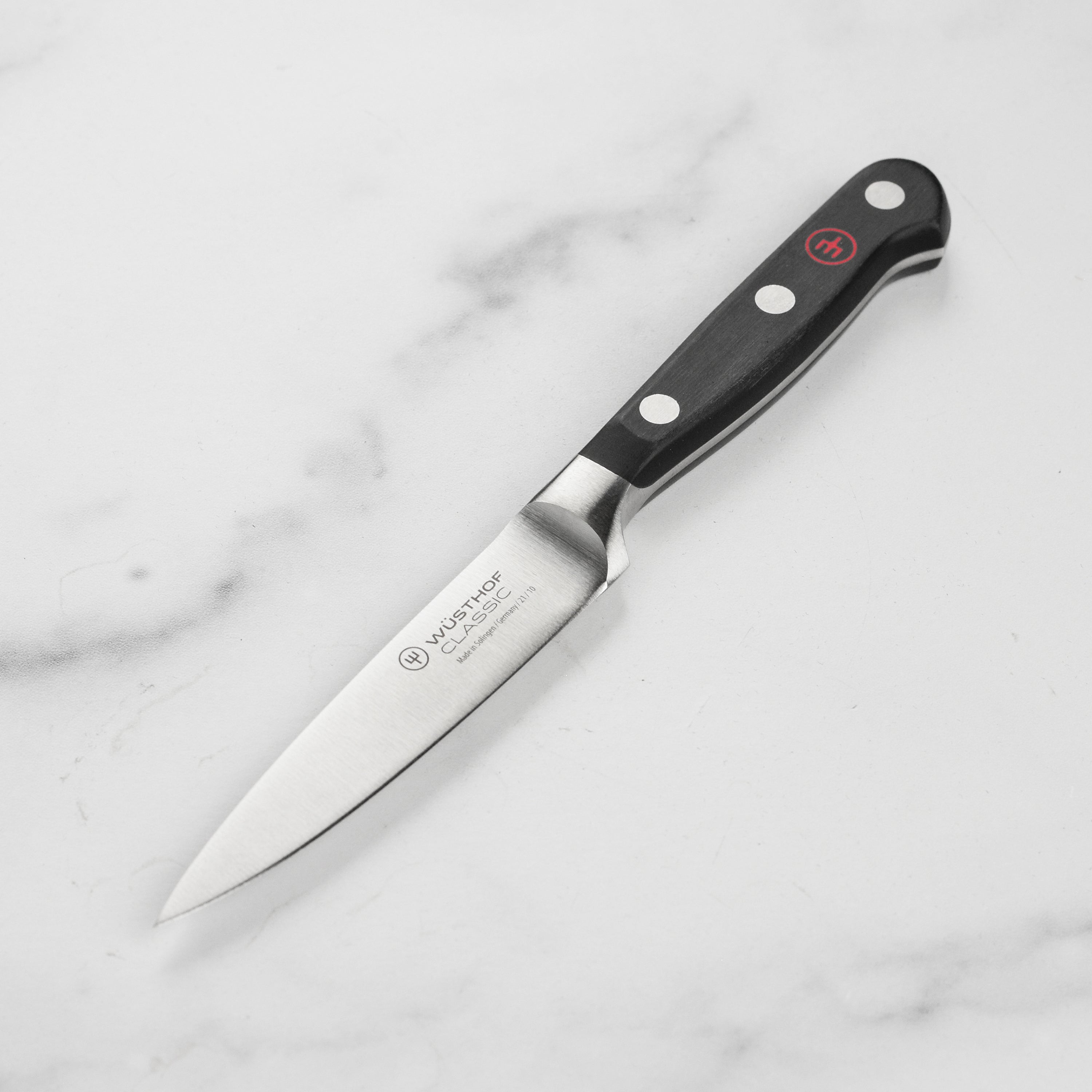 Close-up of the Wusthof Classic 4 inch paring knife cutting citrus — showing blade sharpness and control.