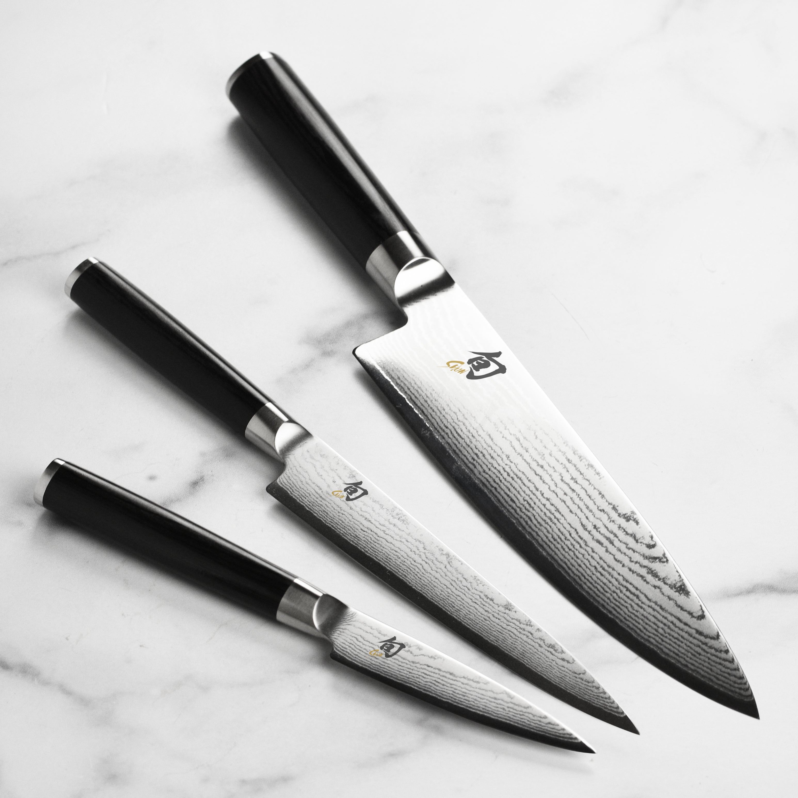 Close-up of the chef knife from the Shun Classic set showing Damascus steel pattern and VG-MAX core