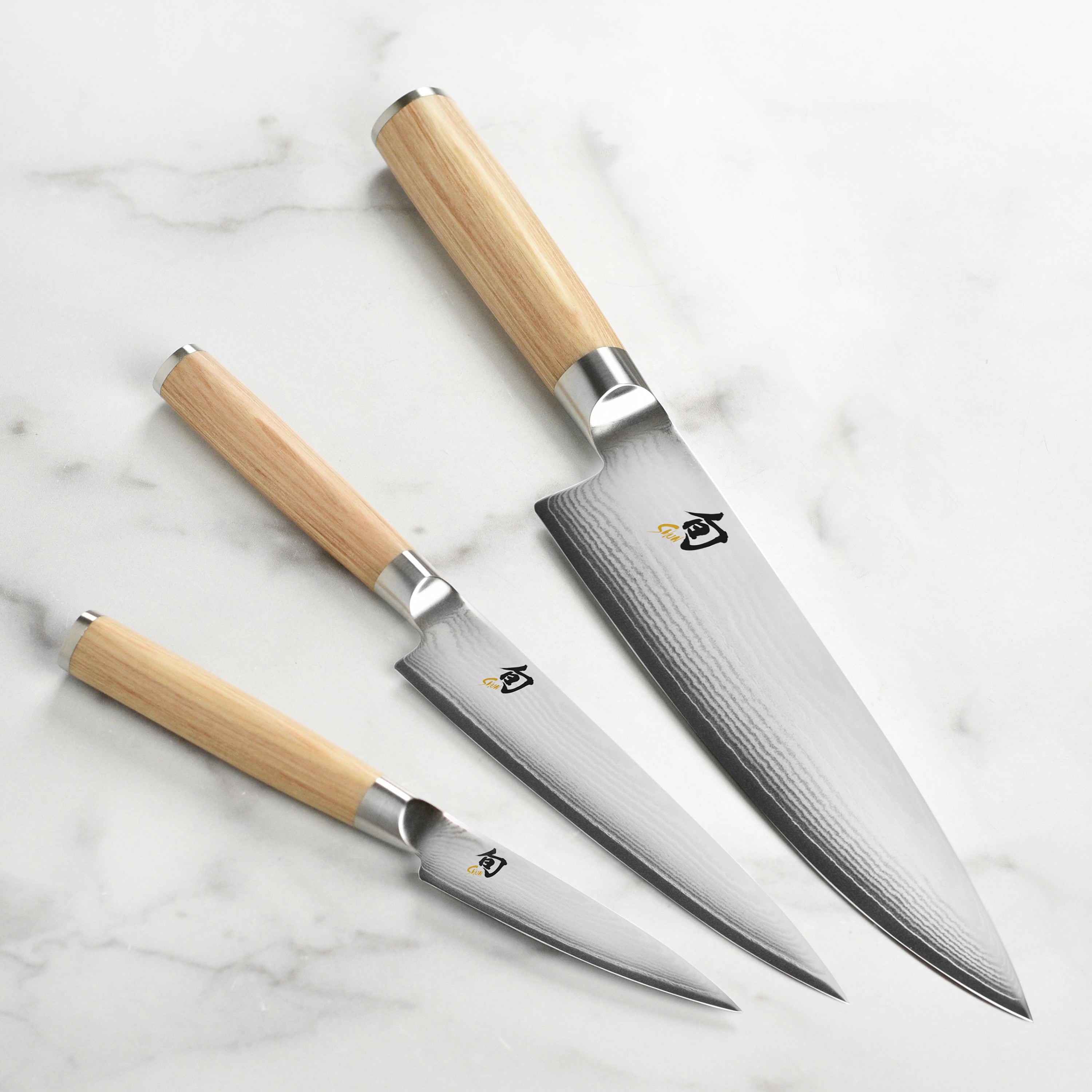 Close-up of Shun Classic Blonde chef knife highlighting its Damascus blade and PakkaWood handle.