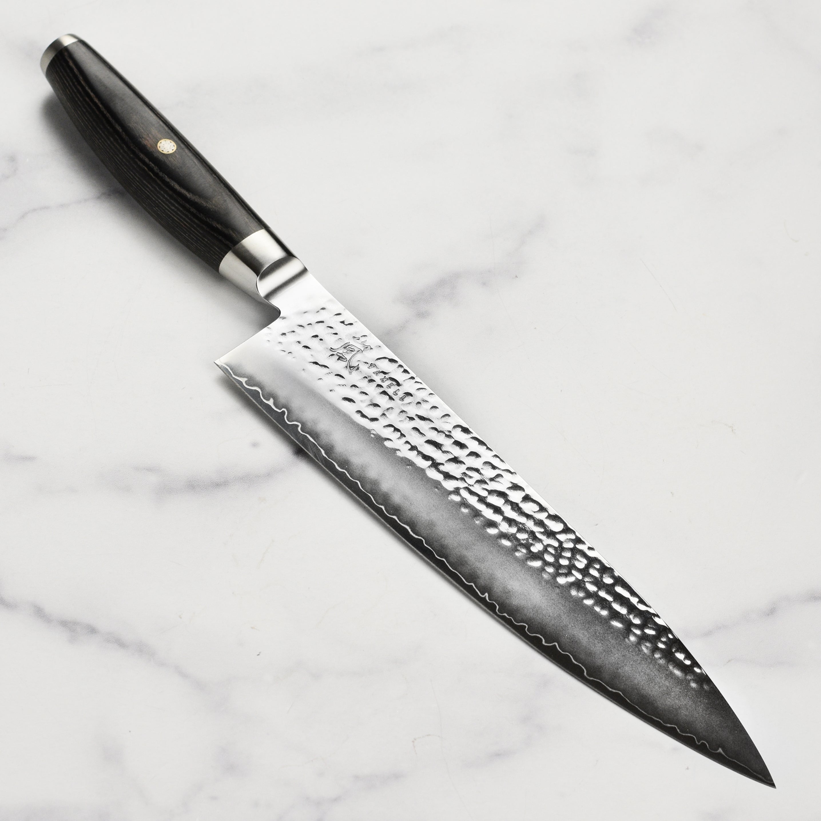 Yaxell Ketu SG2 chef's knife showcasing the hammered blade and pakkawood handle from a side angle.
