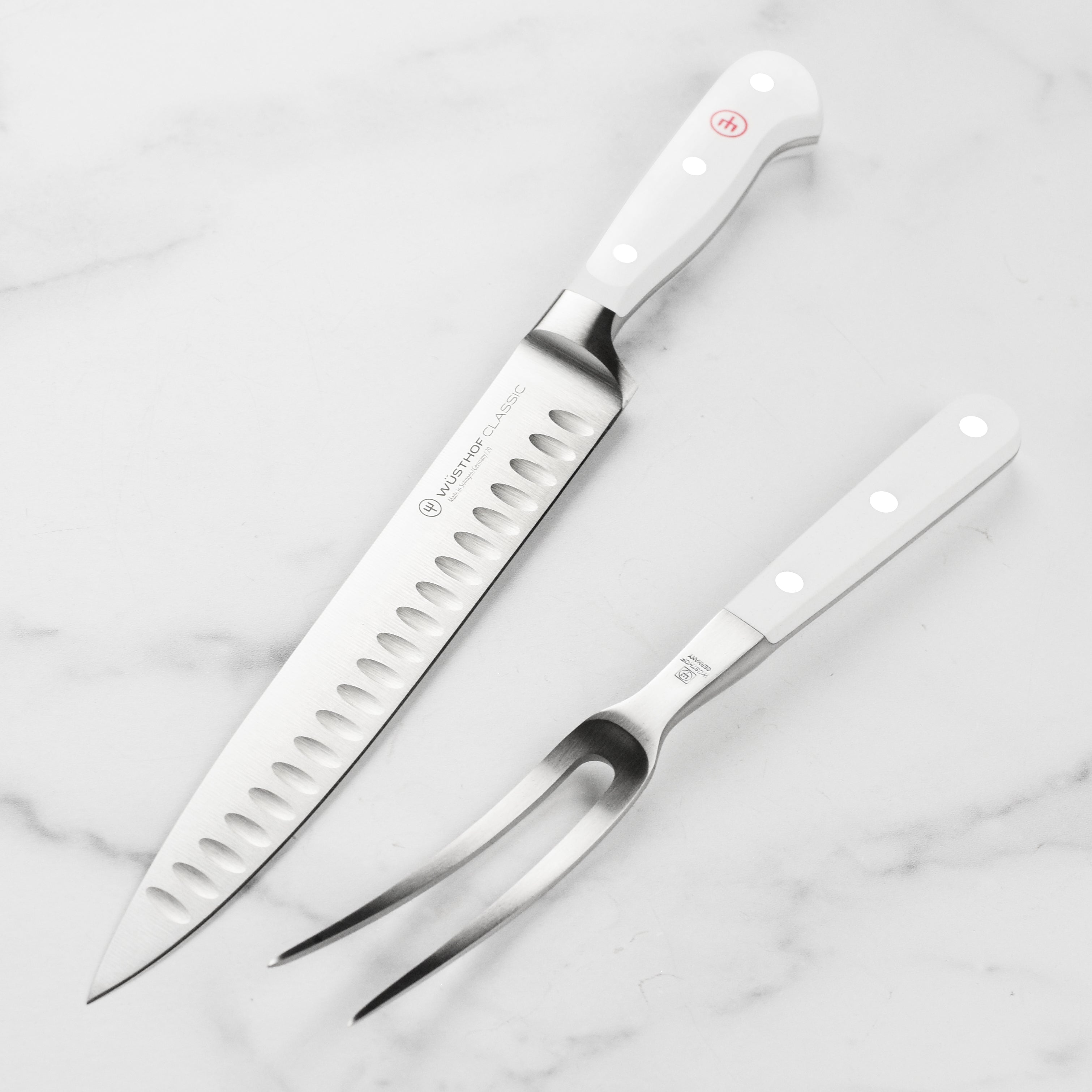 Angle view of the Wüsthof Classic White carving knife set displayed beside sliced roast beef