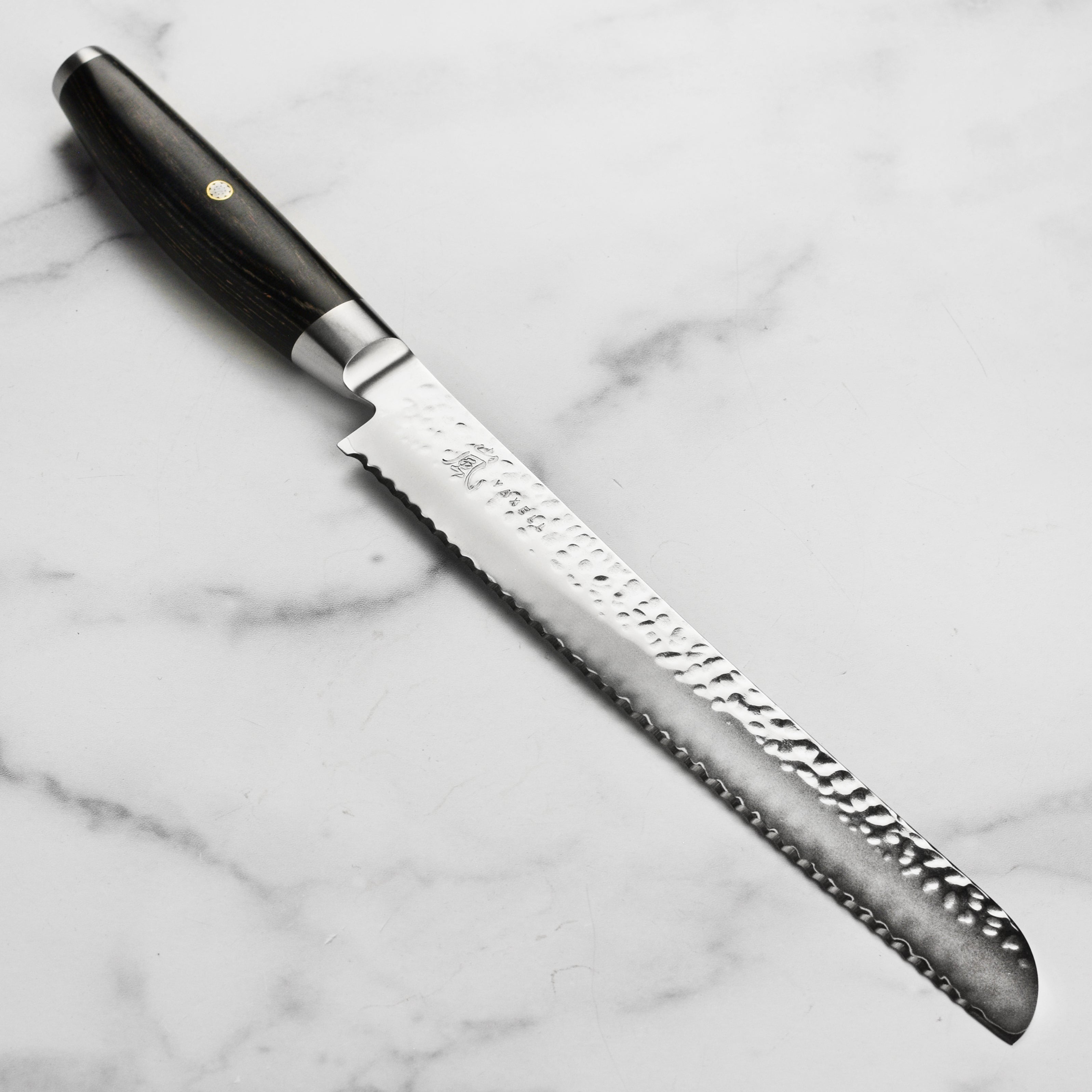 Yaxell Ketu SG2 9-inch Japanese bread knife with hammered blade on cutting board