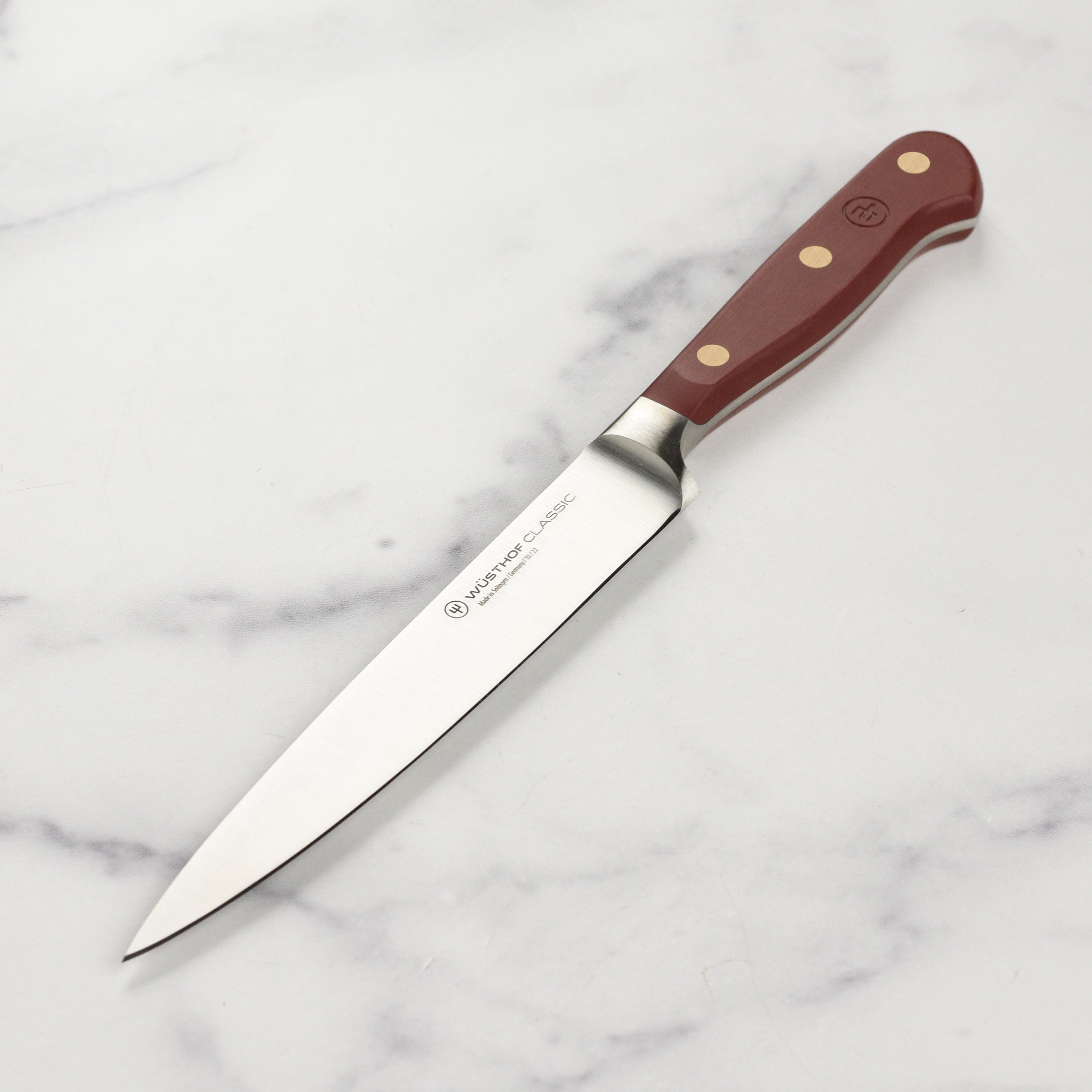 Wusthof Classic utility knife on a wooden cutting board, highlighting its sleek blade and sturdy handle.