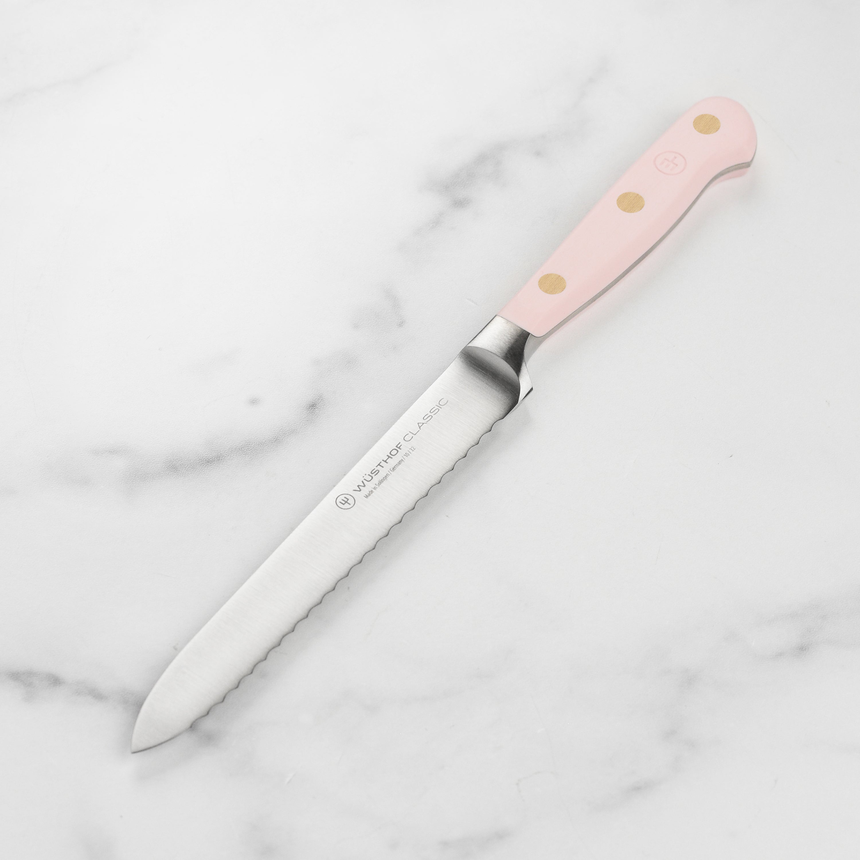 Close-up of the Wüsthof Classic Pink Himalayan Salt Serrated Utility Knife blade highlighting its sharp edge and craftsmanship.