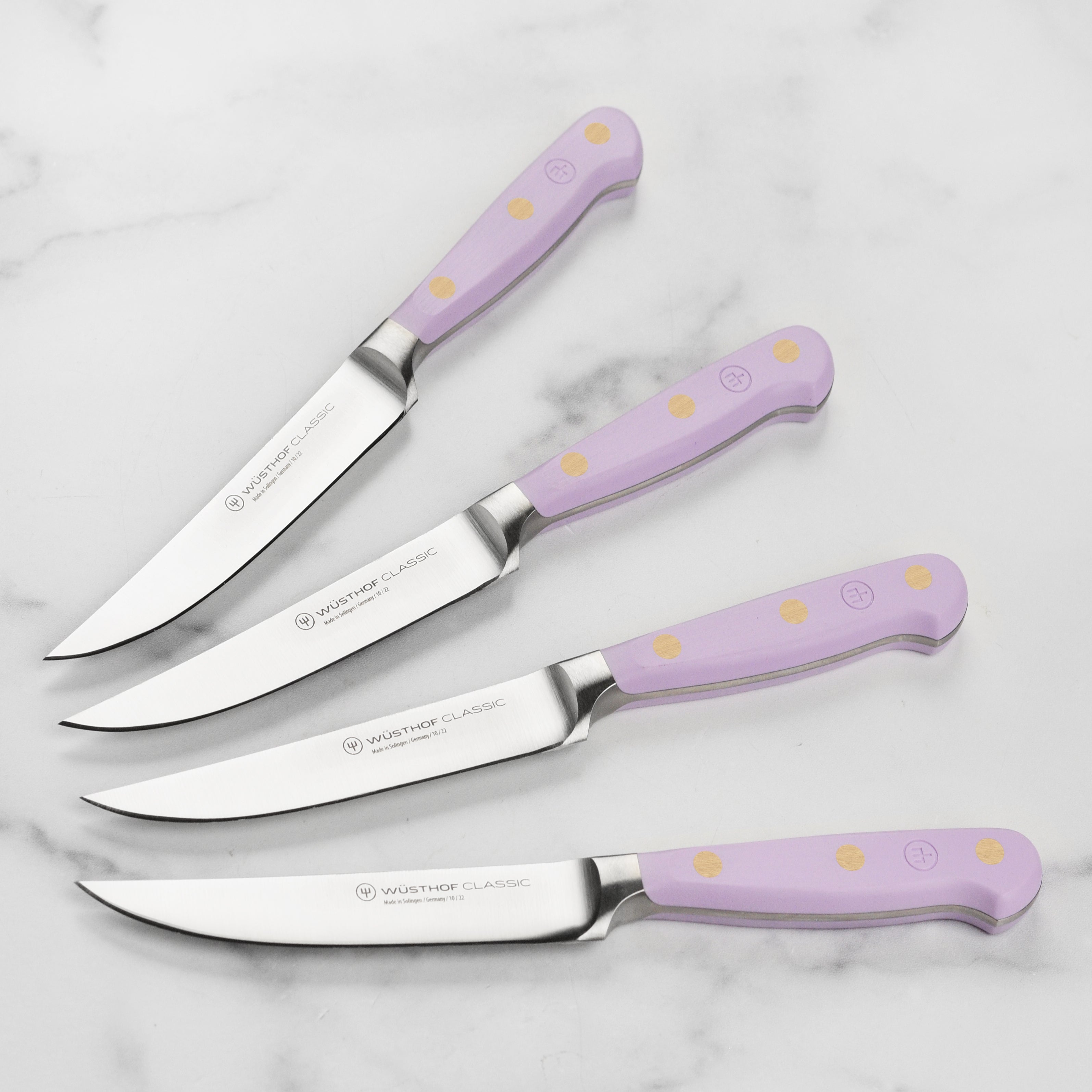 Close-up of Wusthof knives with purple yam handles resting beside grilled steak