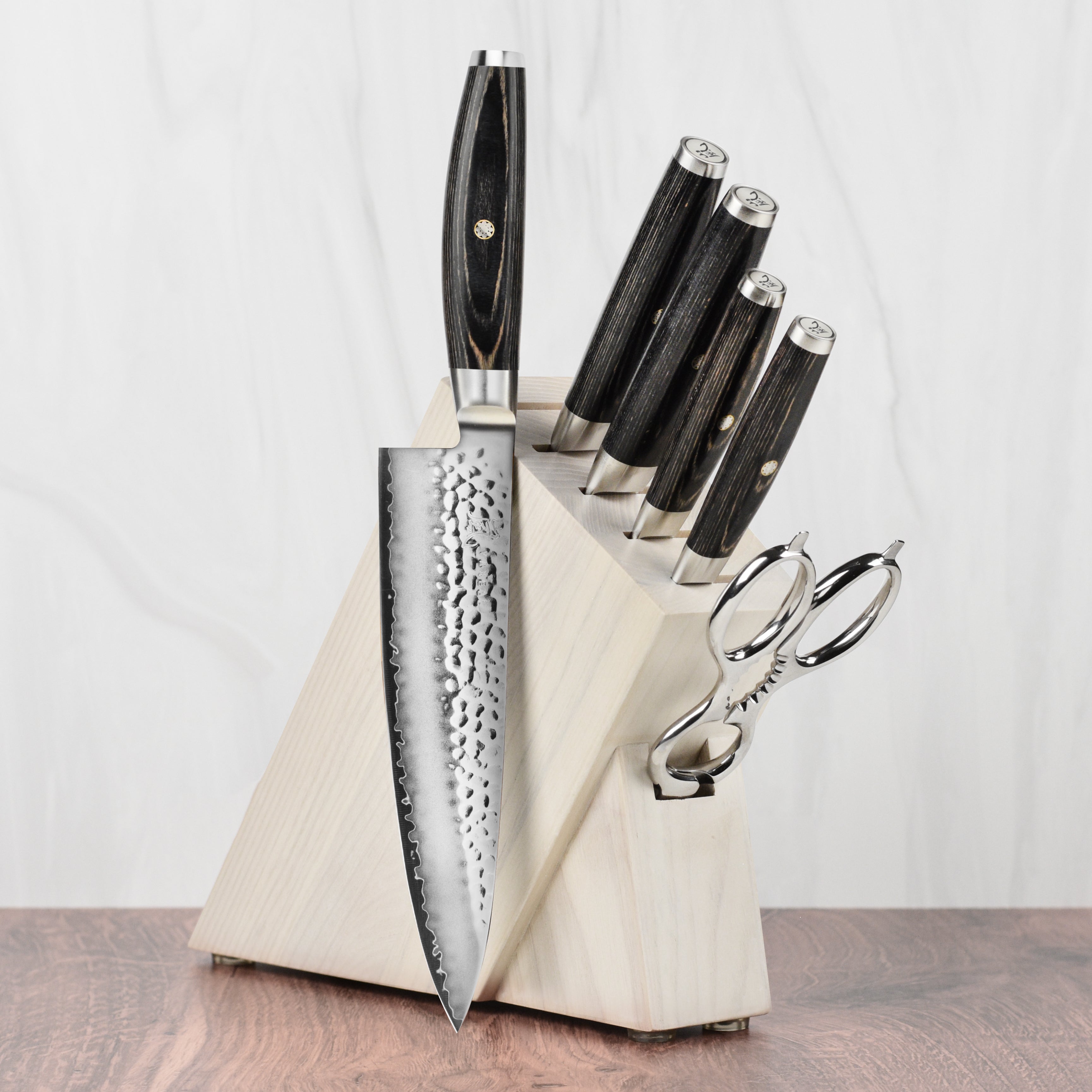 Yaxell Ketu SG2 knife set displayed on a wooden kitchen countertop, highlighting the hammered finish and sleek design.