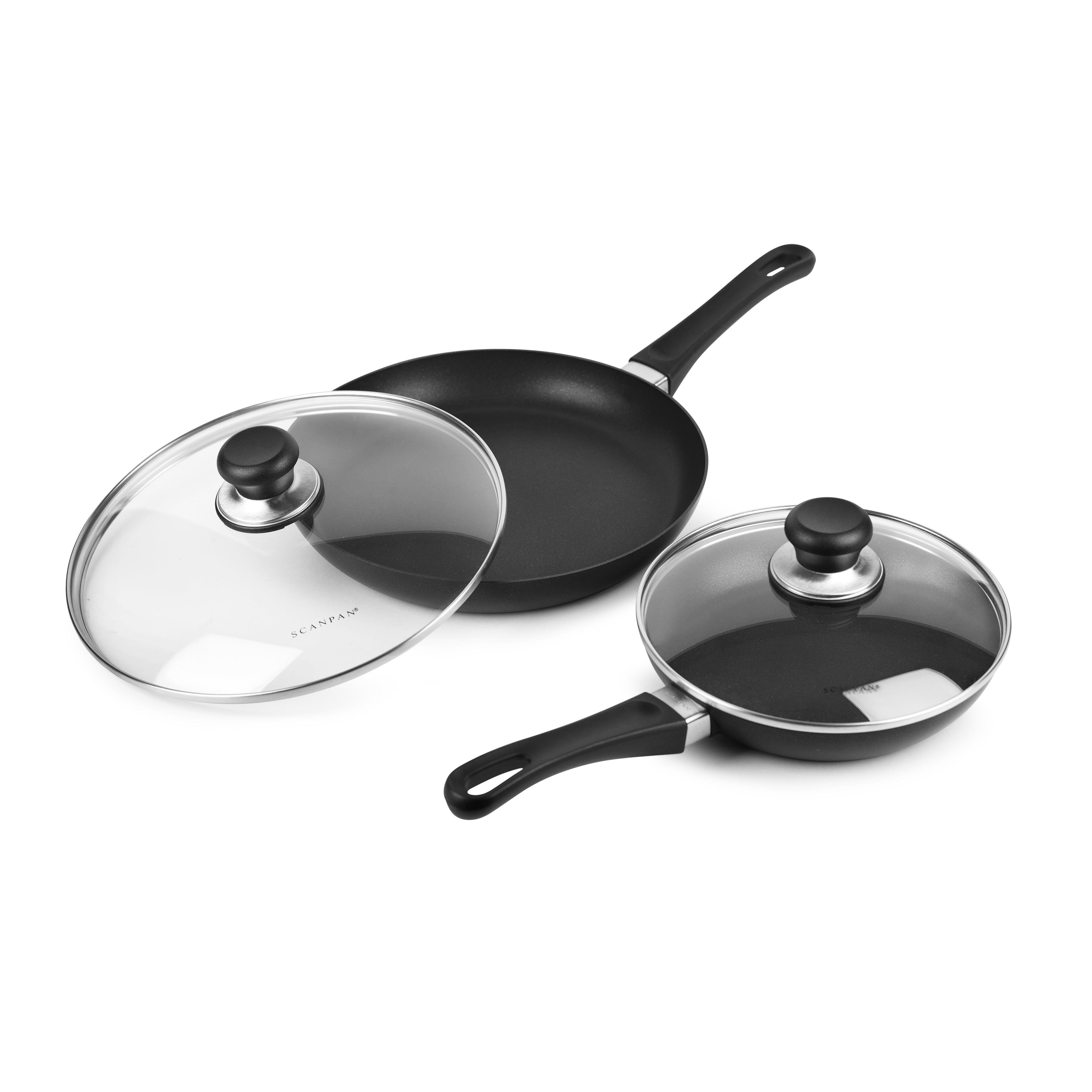 Set of nonstick fry pans with lids on a stovetop, showing even surface and glass lids