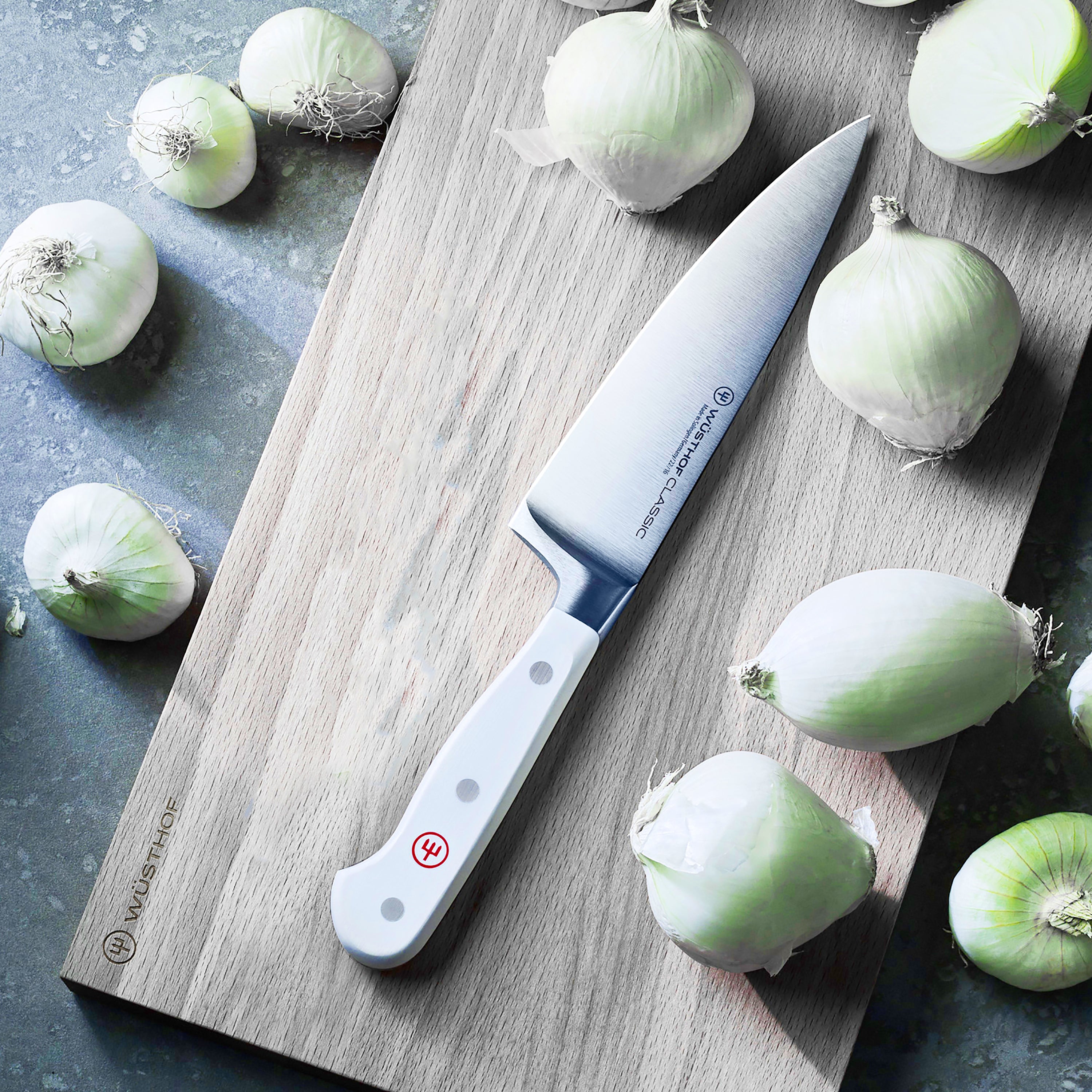 Hand holding the Wüsthof knife slicing vegetables in a modern kitchen